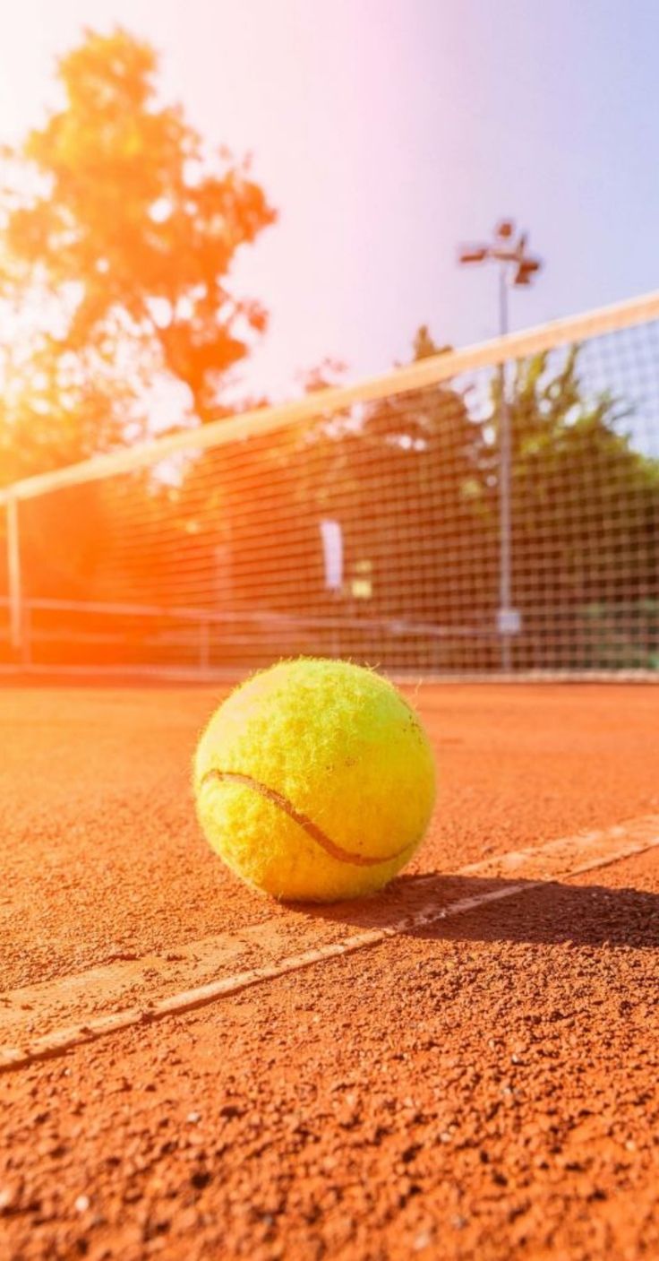 A tennis ball sits on the clay court - Tennis