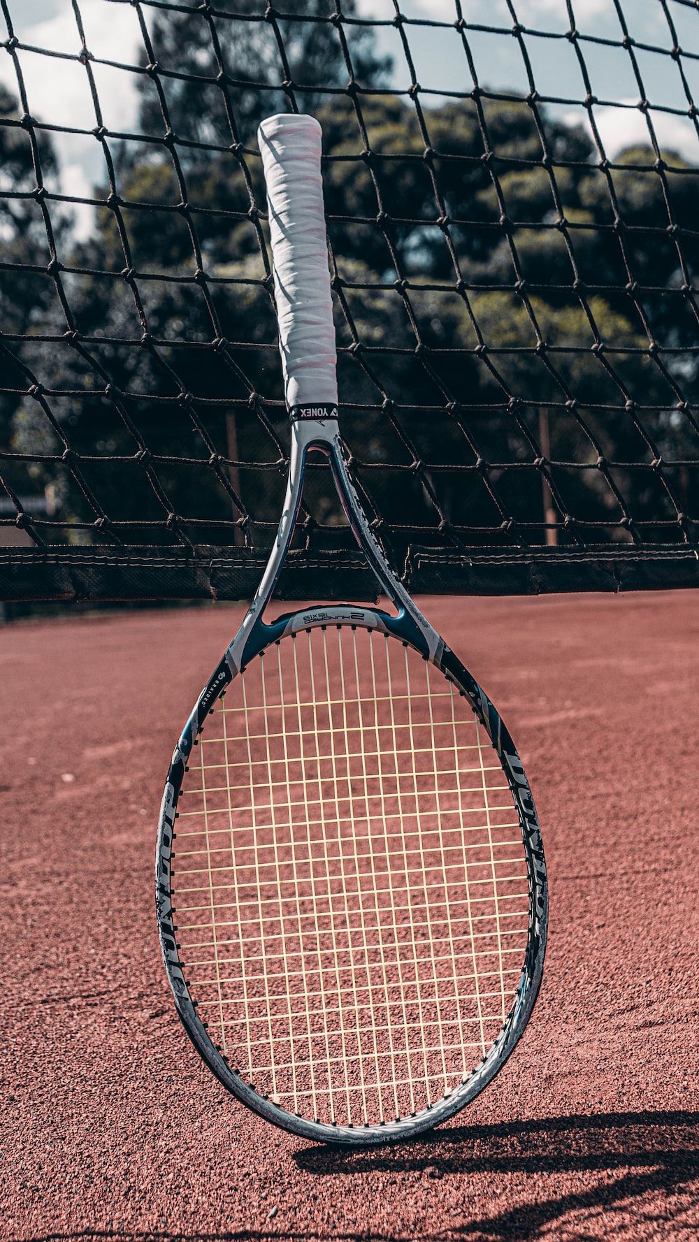 A tennis racket on a tennis court with a net in the background photo