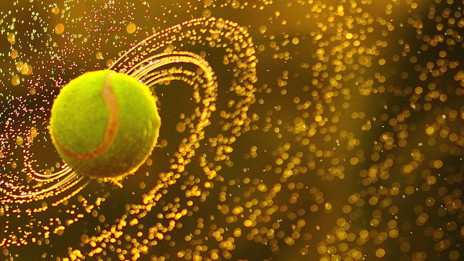 A tennis ball is flying through the air with a golden background. - Tennis