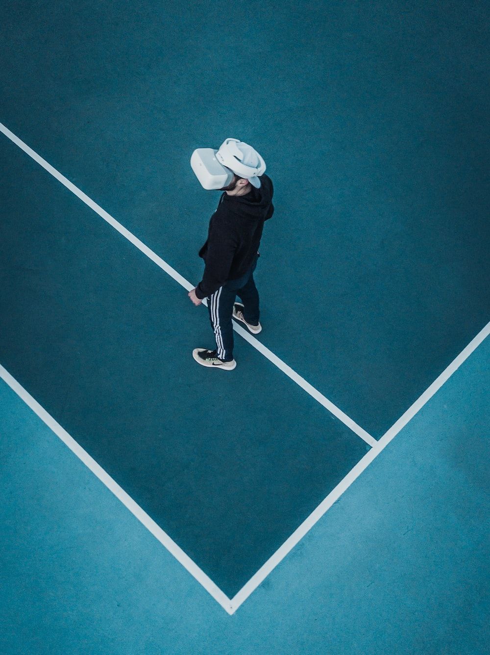 Man in track suit wearing VR headset standing on tennis court photo
