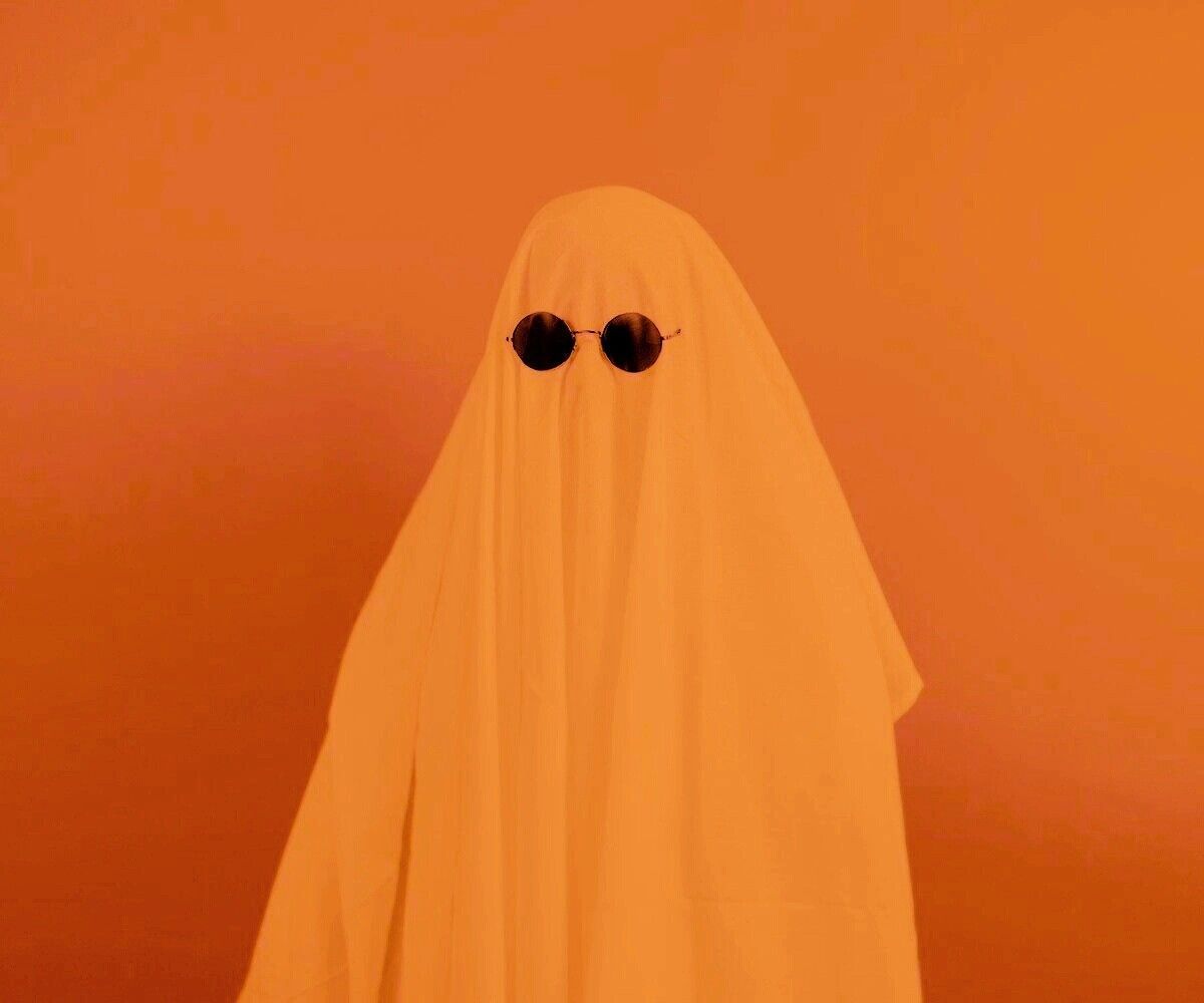 A person wearing sunglasses and an orange ghost costume - Ghost