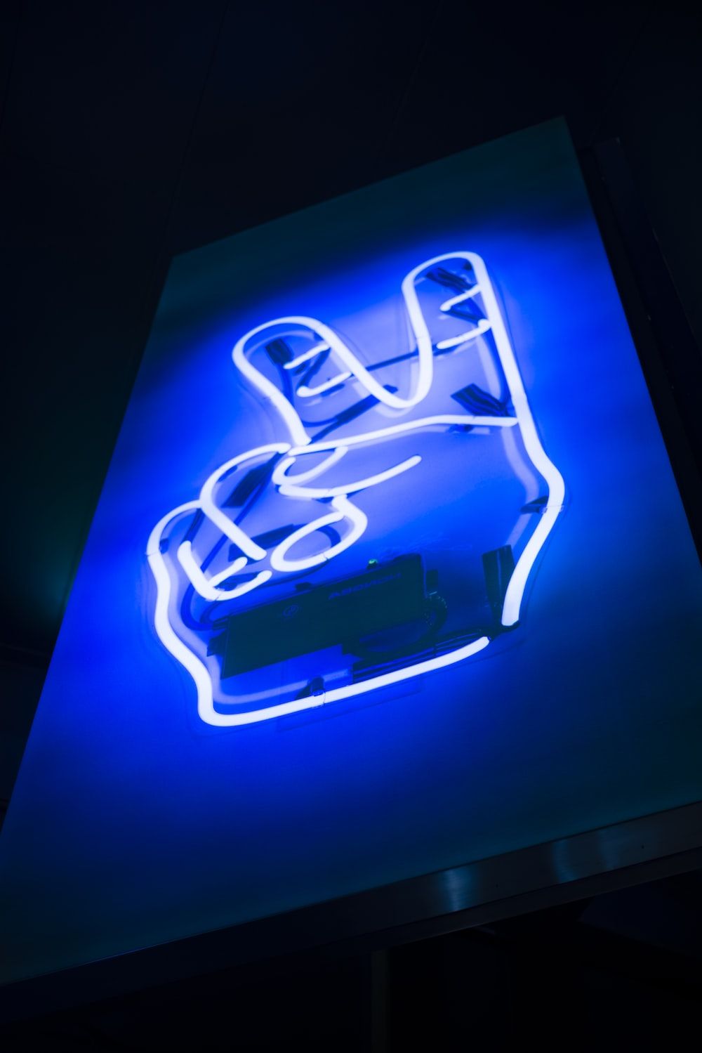 A neon sign of a hand making the peace sign - Neon blue