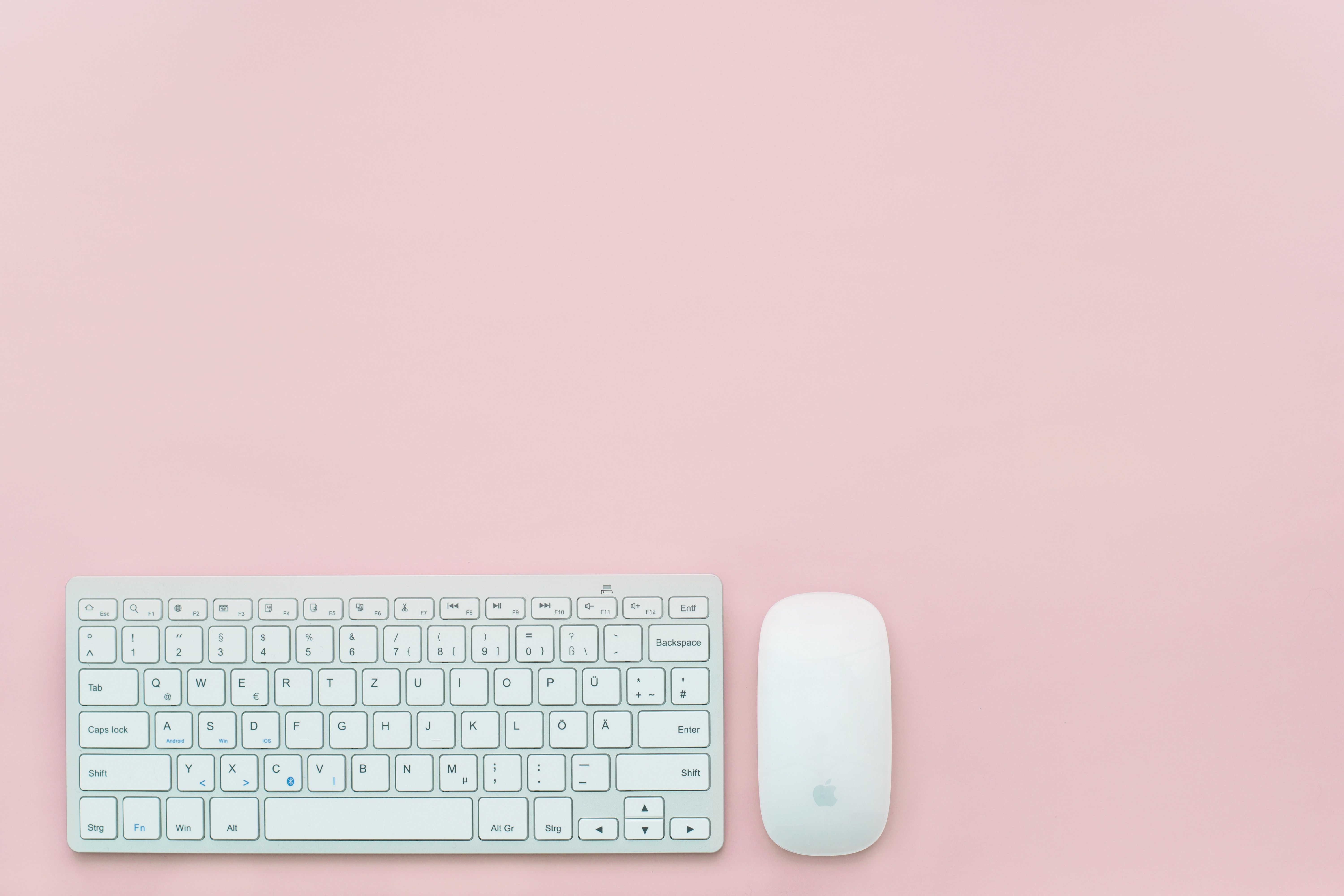 A white keyboard and mouse on a pink background - Technology