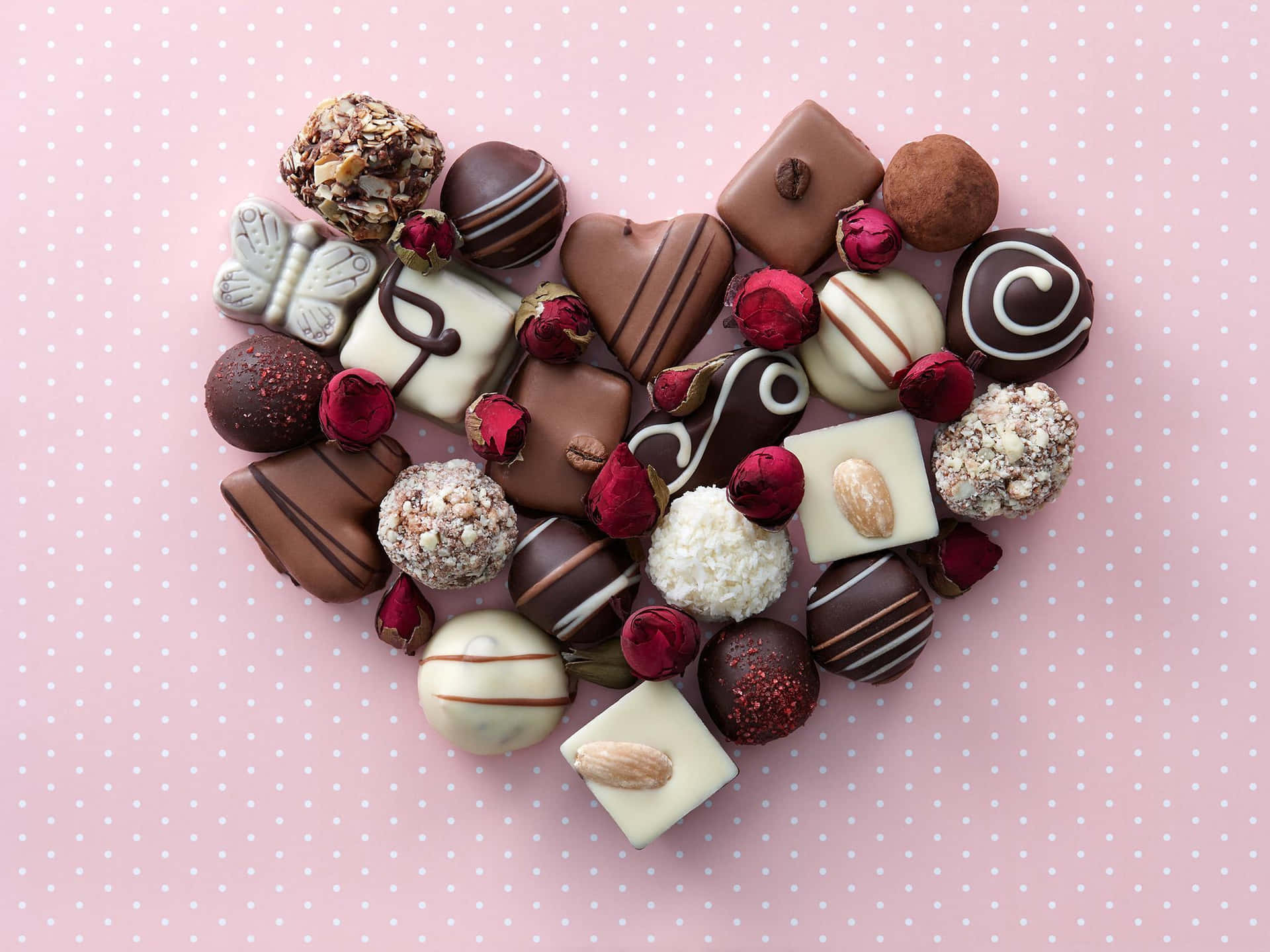 Chocolates arranged in a heart shape on a pink background - Chocolate