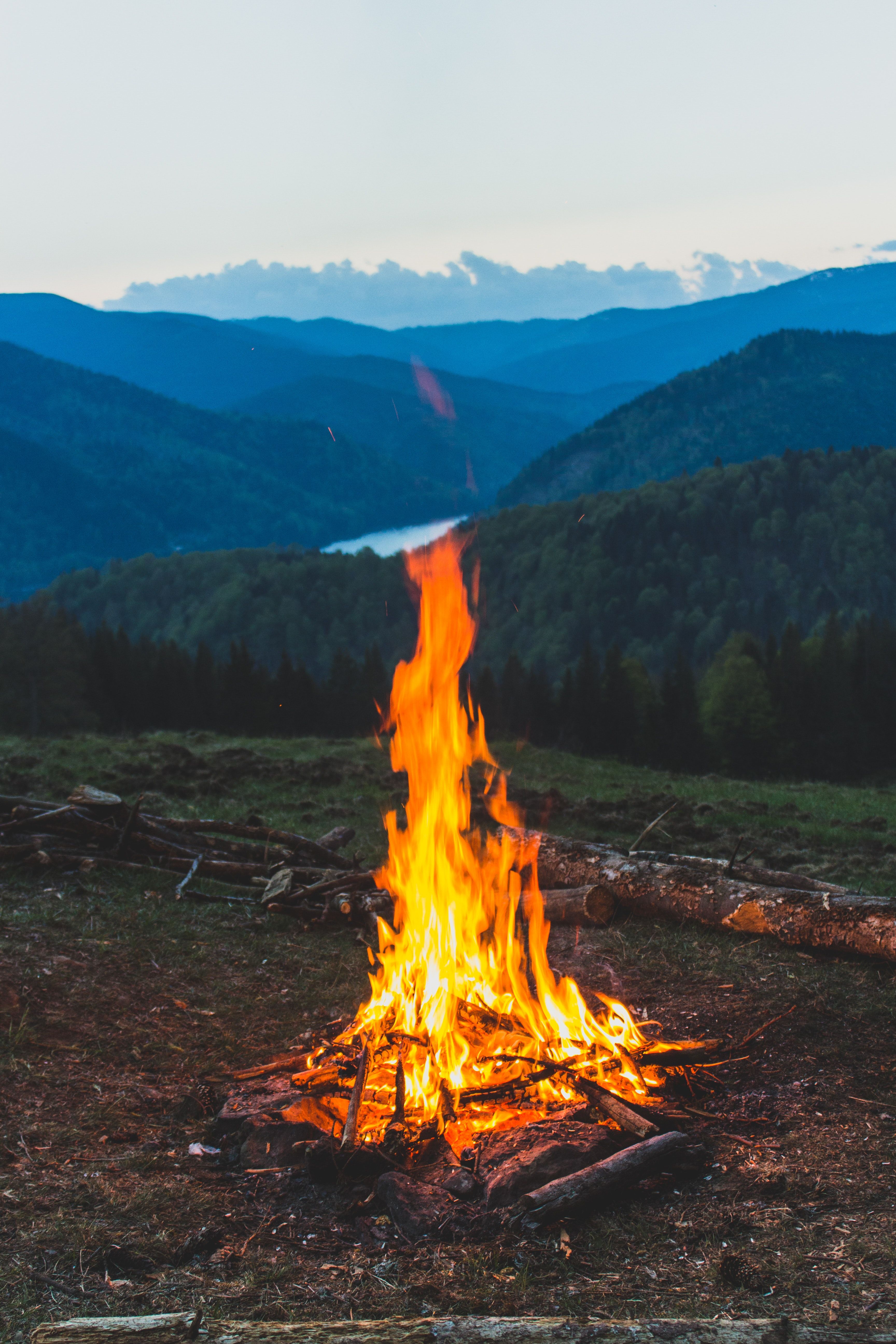 A bonfire burns in the foreground of a mountain landscape. - Camping