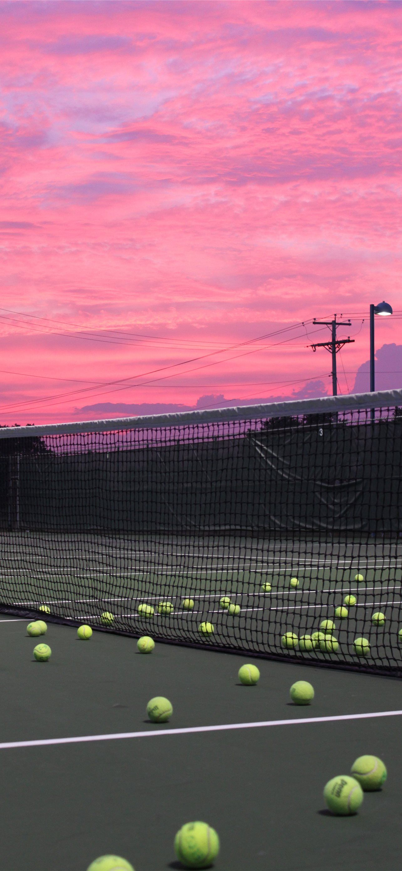 Tennis balls on a tennis court with a pink sky - Tennis