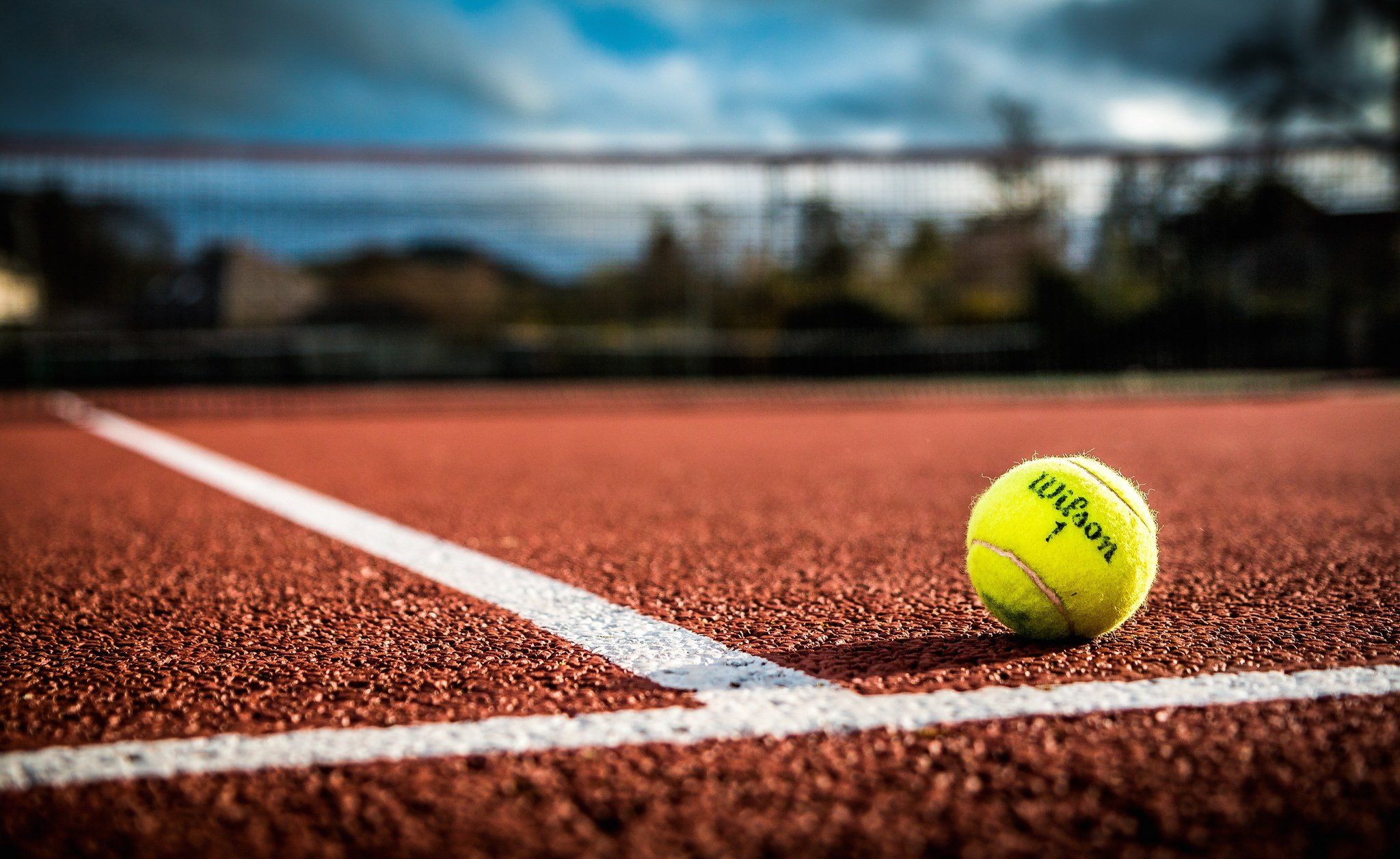 A tennis ball on the line of a tennis court - Tennis