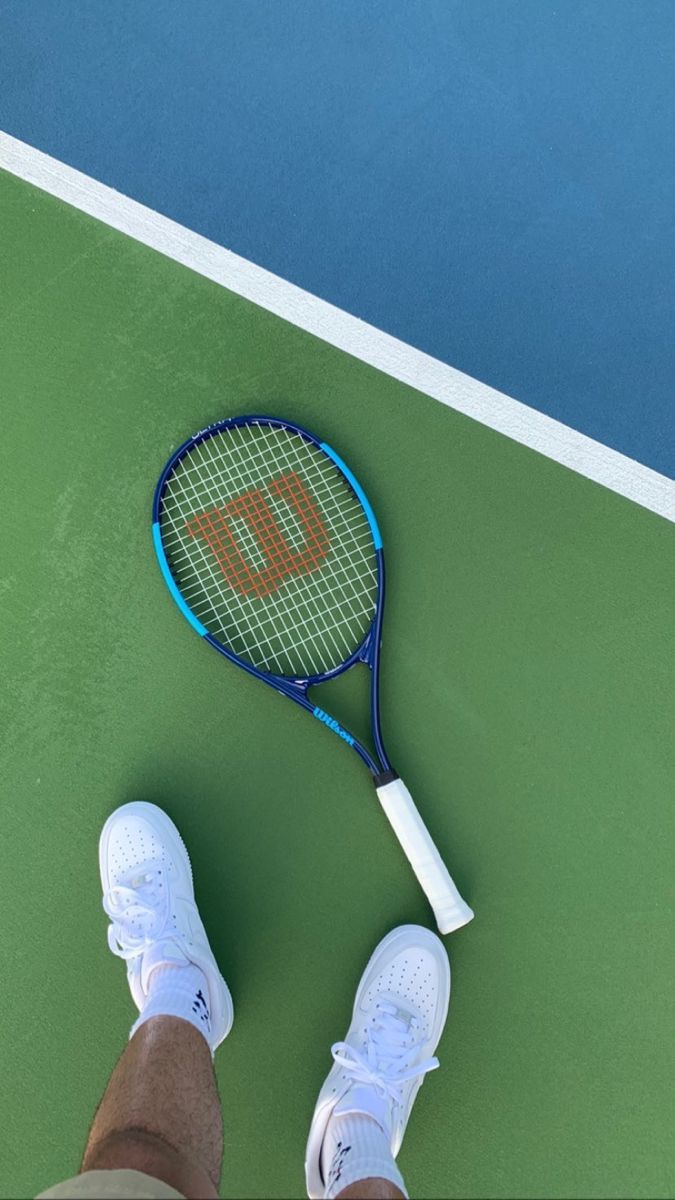 A tennis racket and shoes on top of green court - Tennis