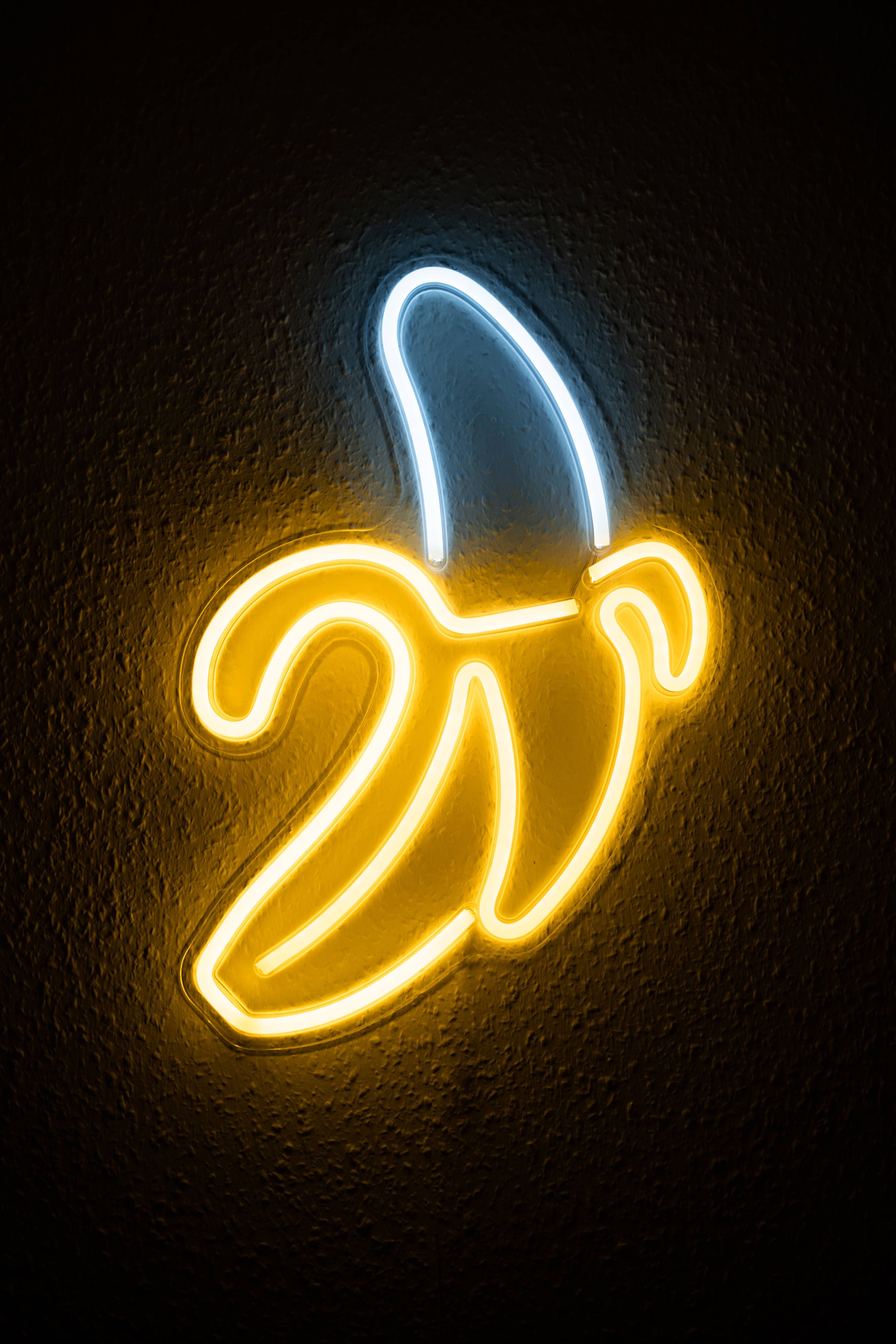 A neon banana sign is lit up on the wall - Banana