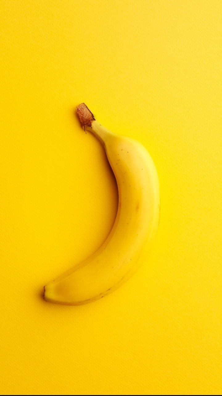 A single banana on top of yellow background - Banana