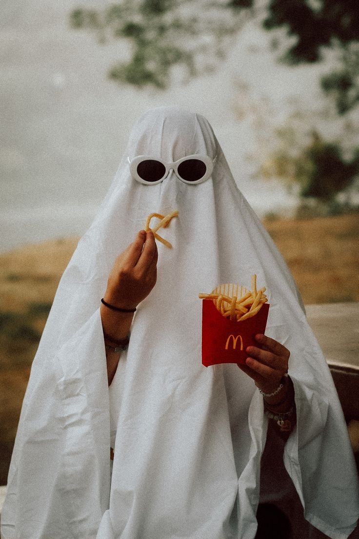 A person in white robe eating french friess - Ghost
