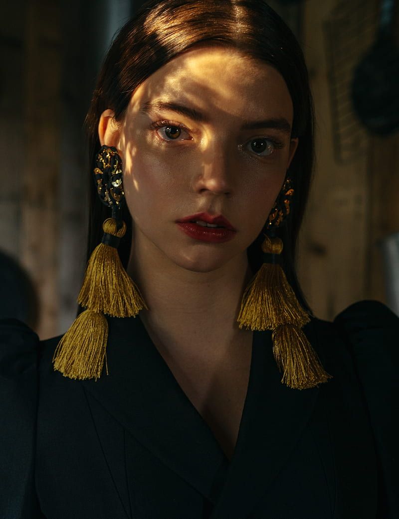 A model wears a black top and gold tassel earrings - Anya Taylor-Joy