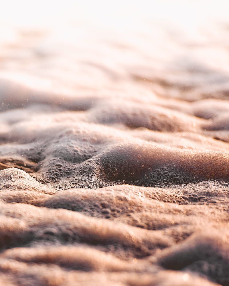 A close-up of sand and water on a beach. - Macro
