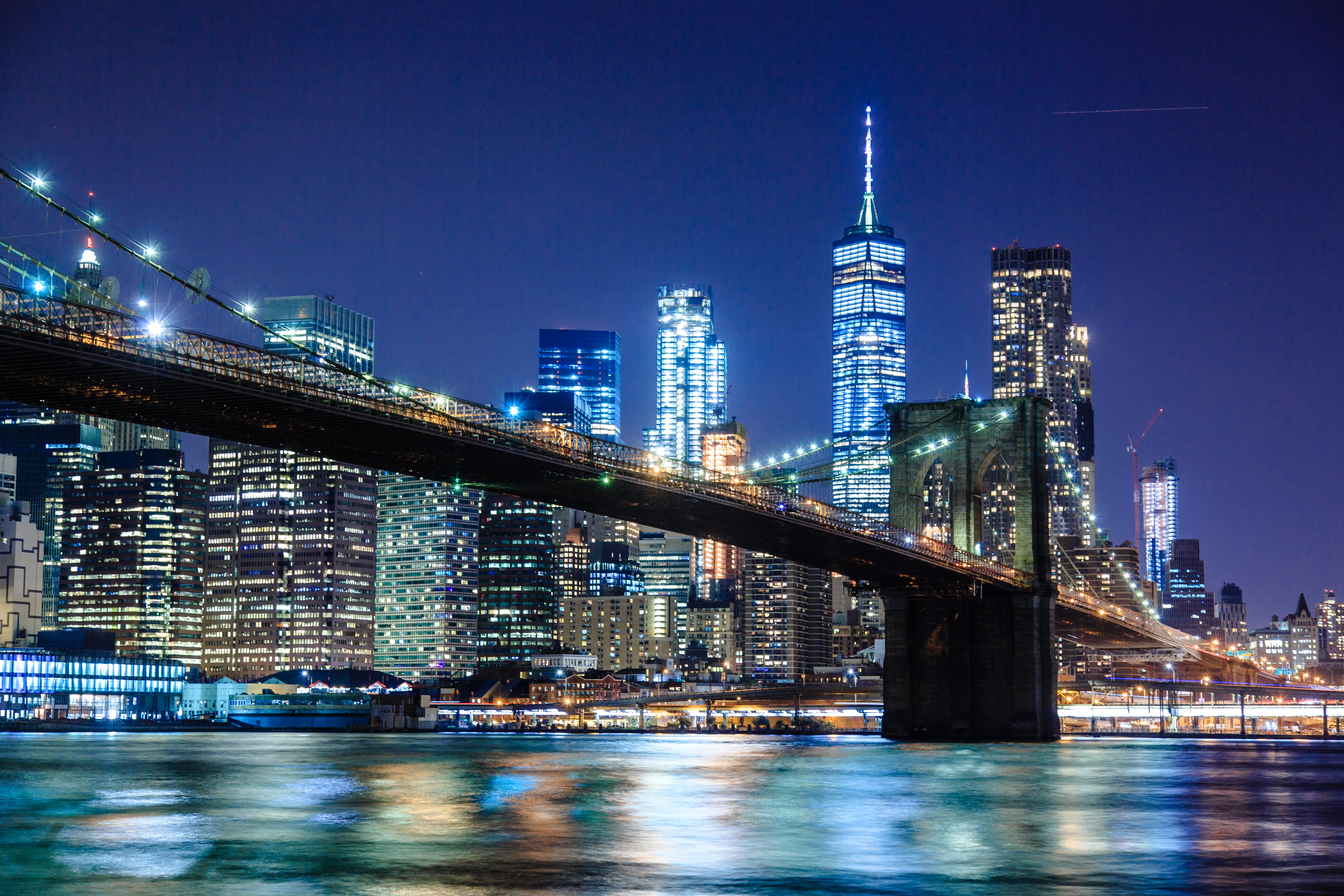A night time view of the Brooklyn Bridge and the Lower Manhattan skyline. - New York