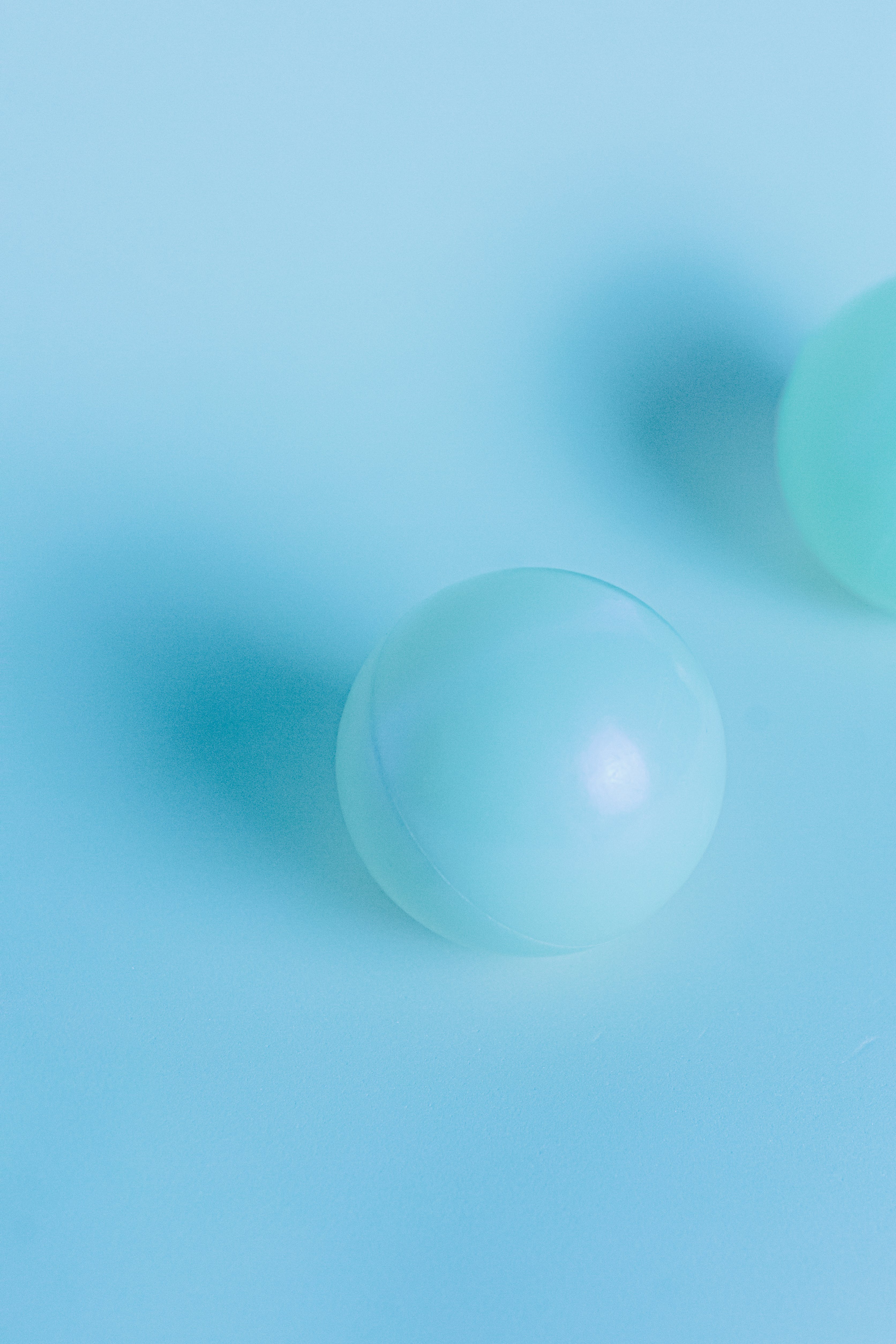 Three blue-green spheres on a blue background - Pastel blue