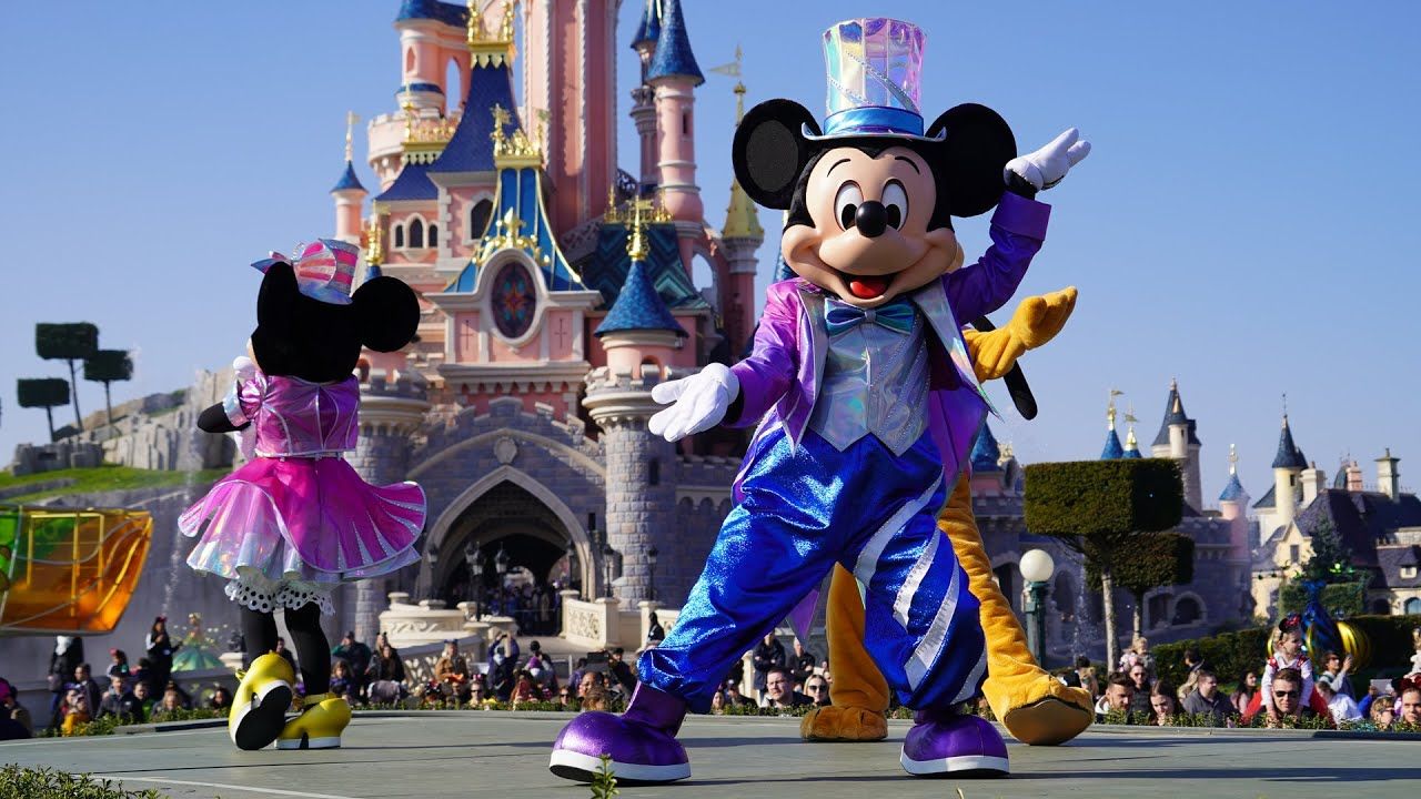 Mickey Mouse and friends dancing in front of a castle. - Disneyland
