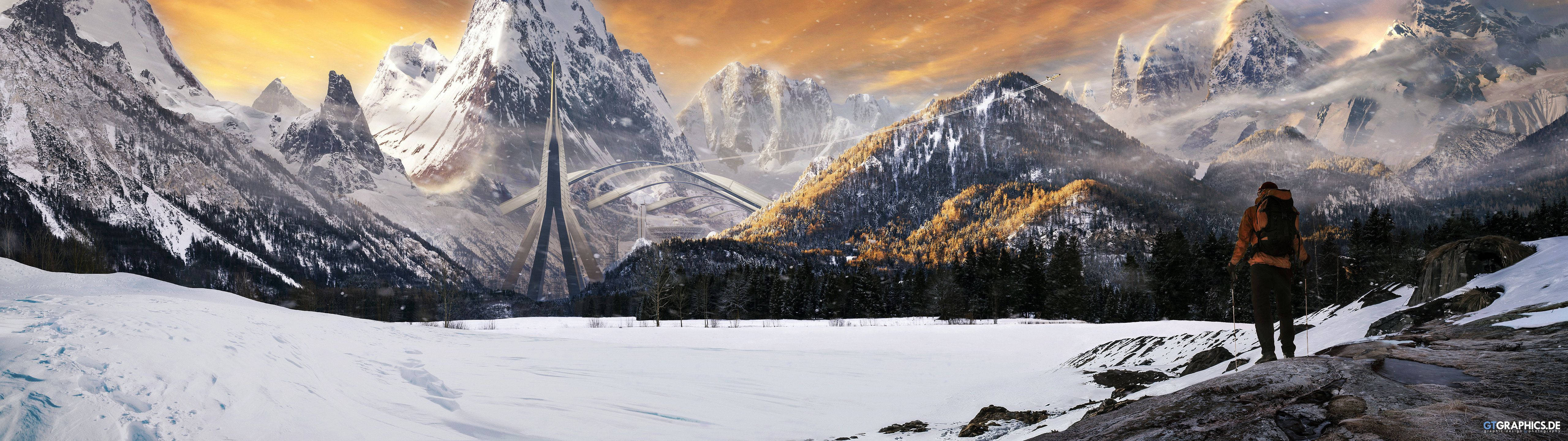 A man standing on a snowy mountain looking at a bridge in the distance. - 5120x1440