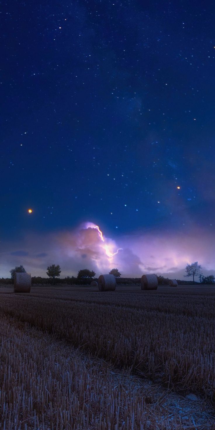 A field with hay bales and stars in the sky - Farm