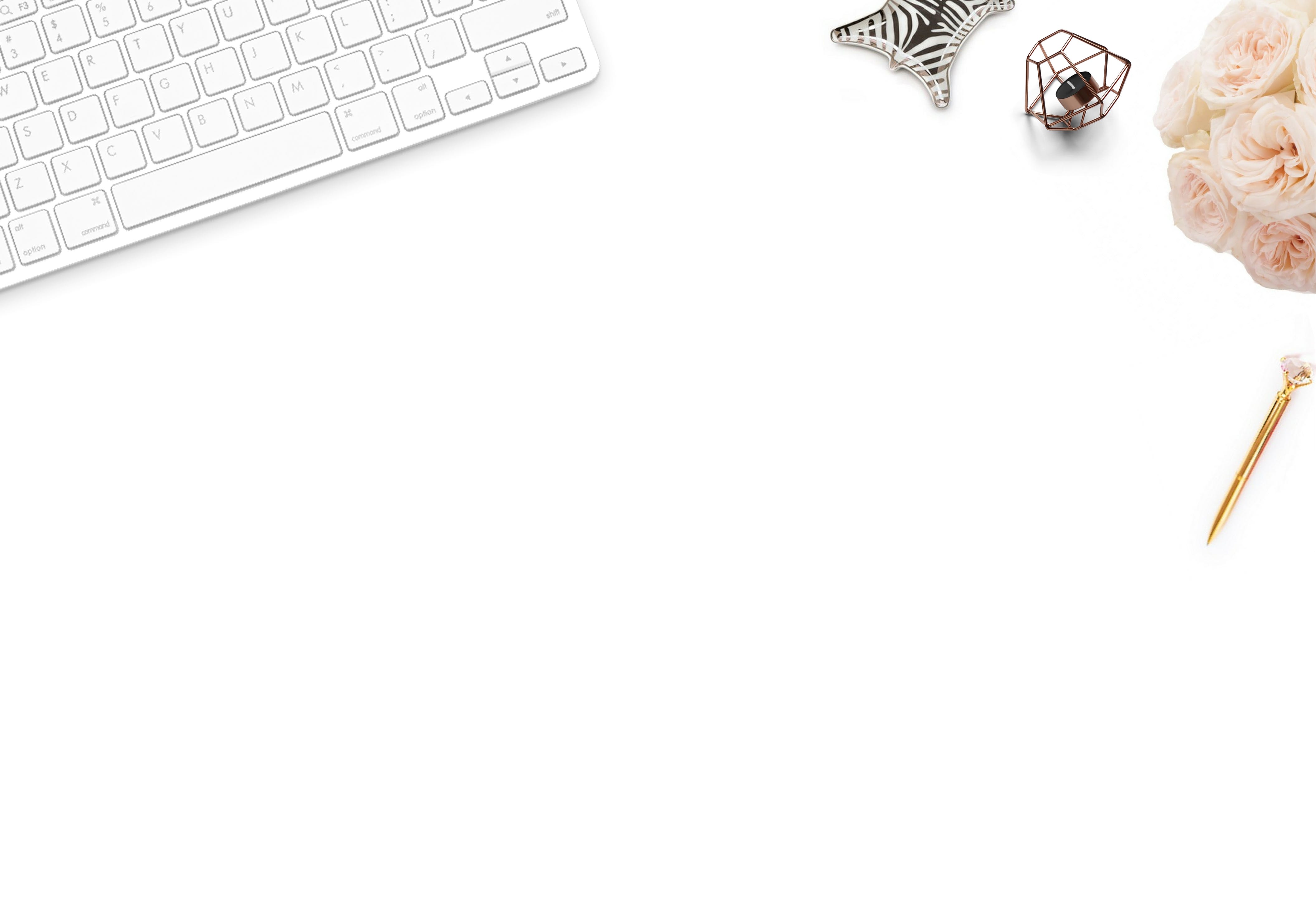 A white desk with a keyboard, mouse, and a vase of flowers. - Flat lay
