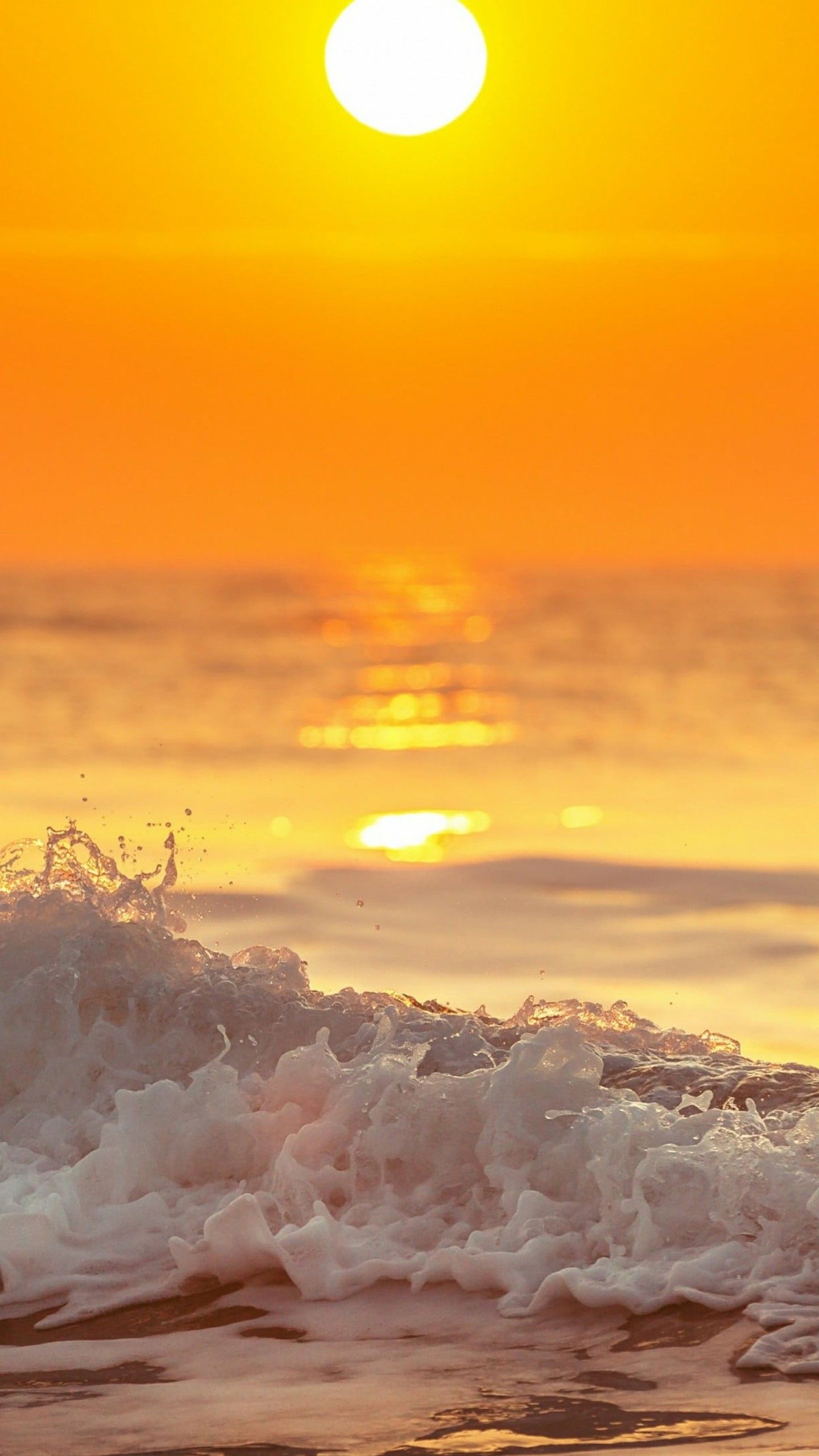 A beautiful sunset over the ocean with a wave crashing in the foreground. - Sunrise