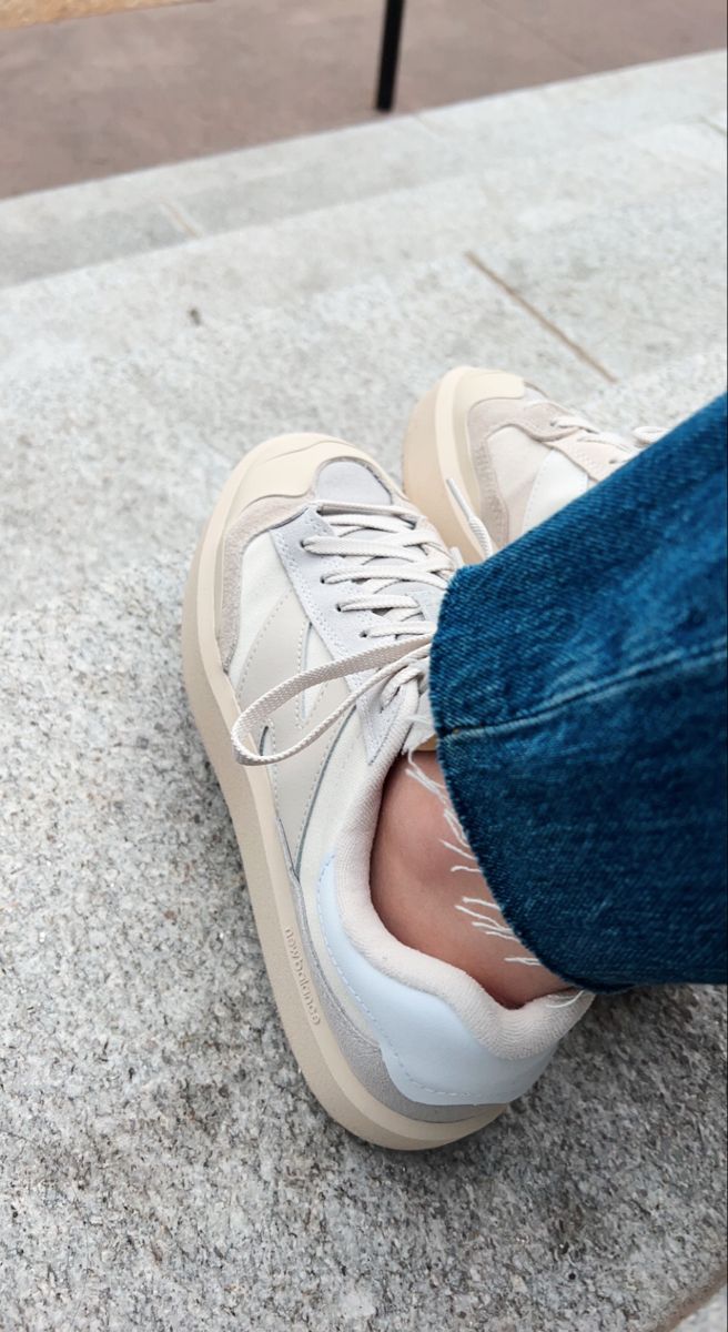 A person wearing white sneakers and blue jeans - New Balance