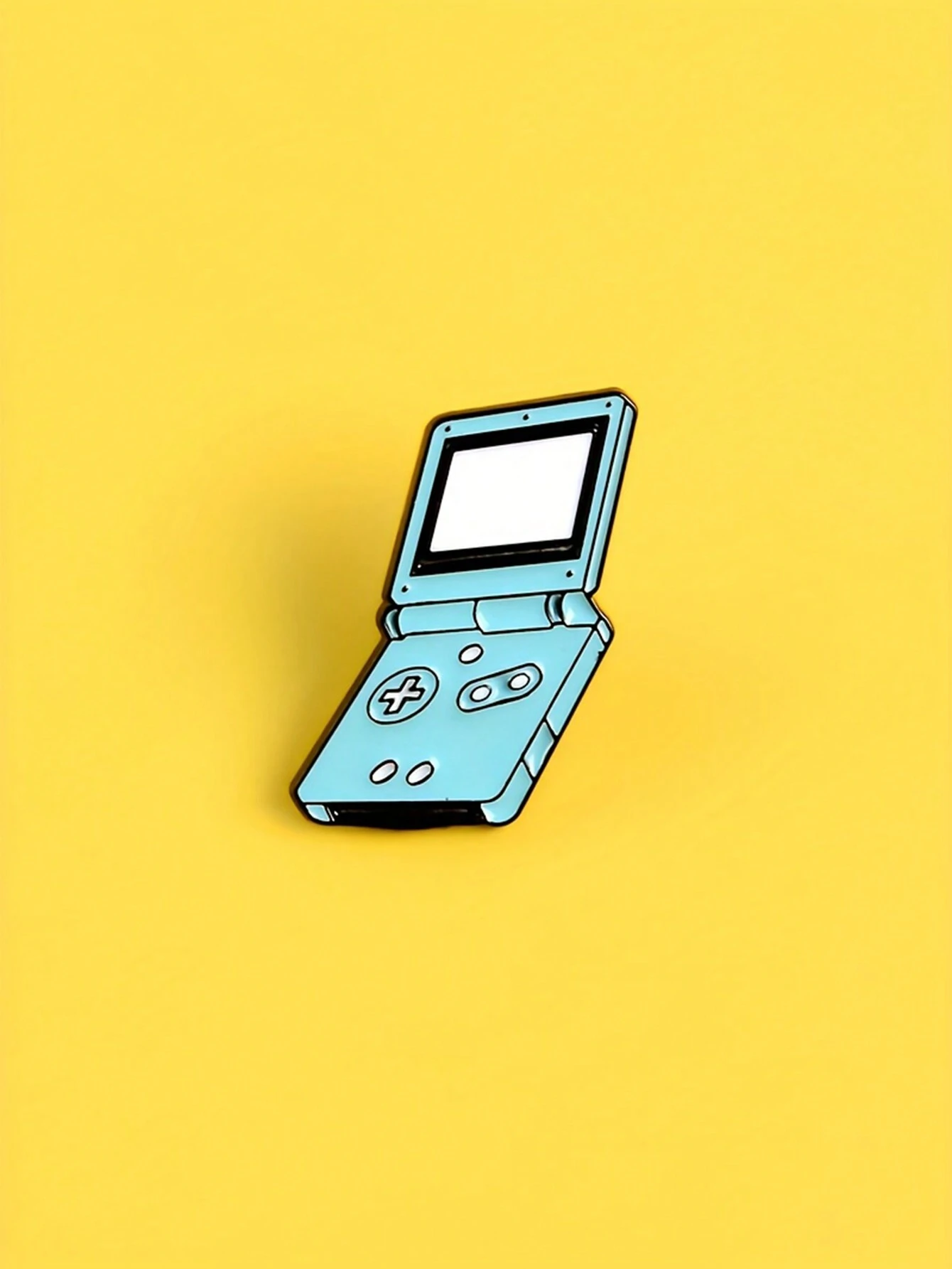 A cute blue and black Nintendo Gameboy Advance soft enamel pin on a yellow background - Game Boy