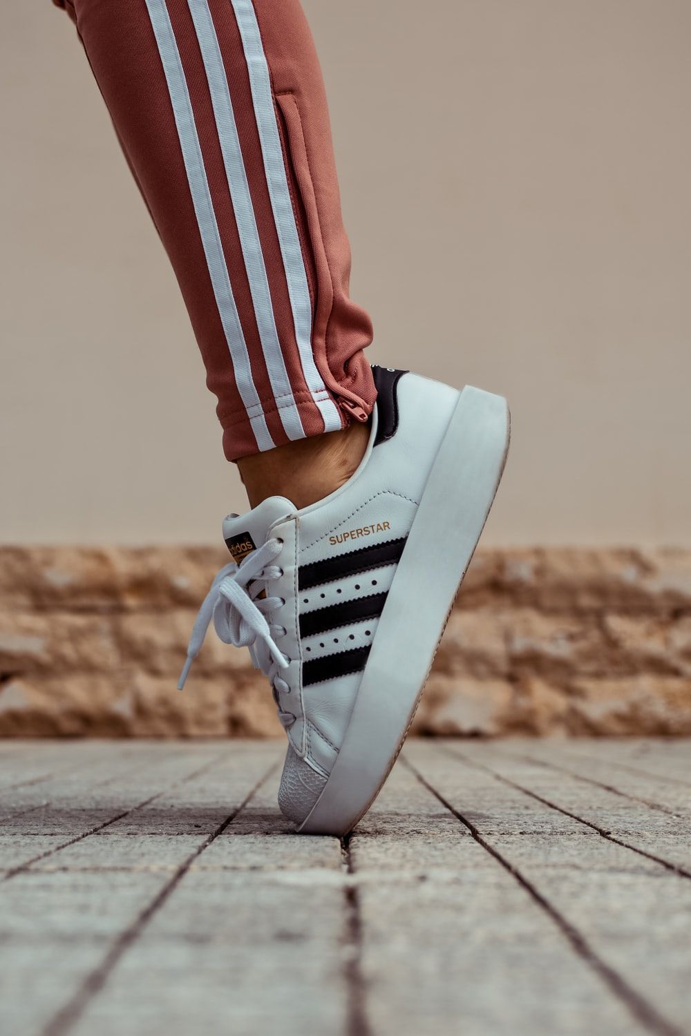 A person wearing white and black Adidas sneakers. - Adidas