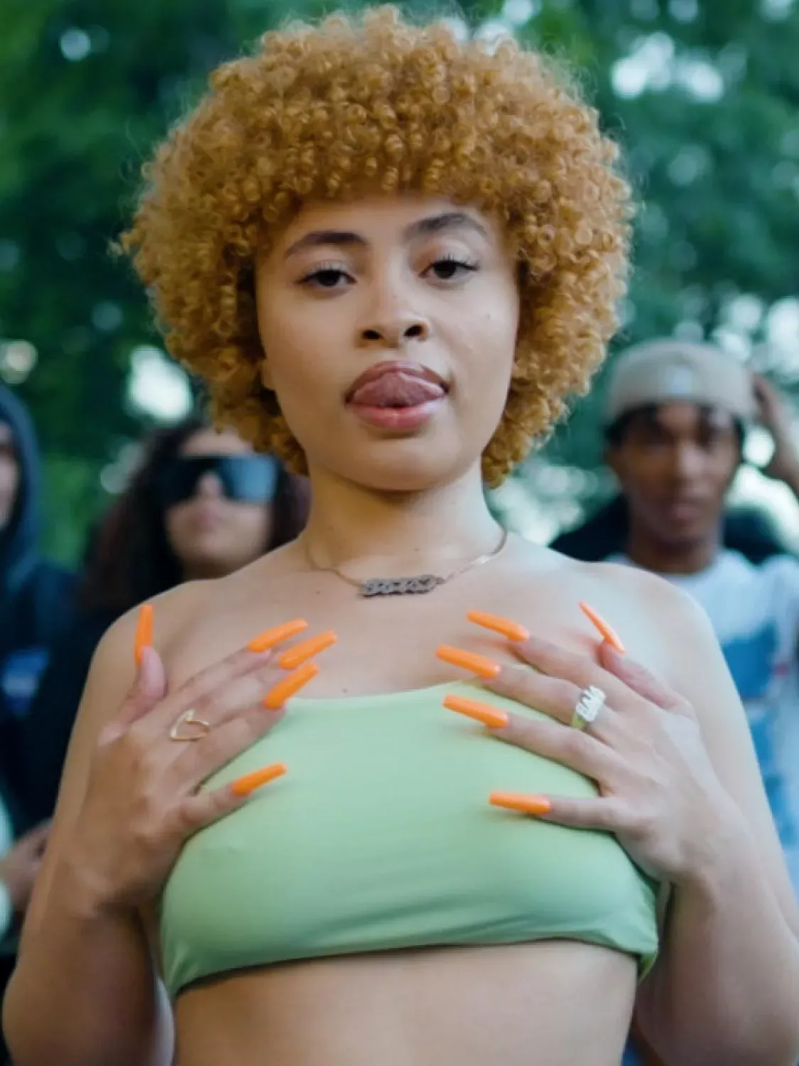 A woman with orange nails and an orange afro. - Ice Spice