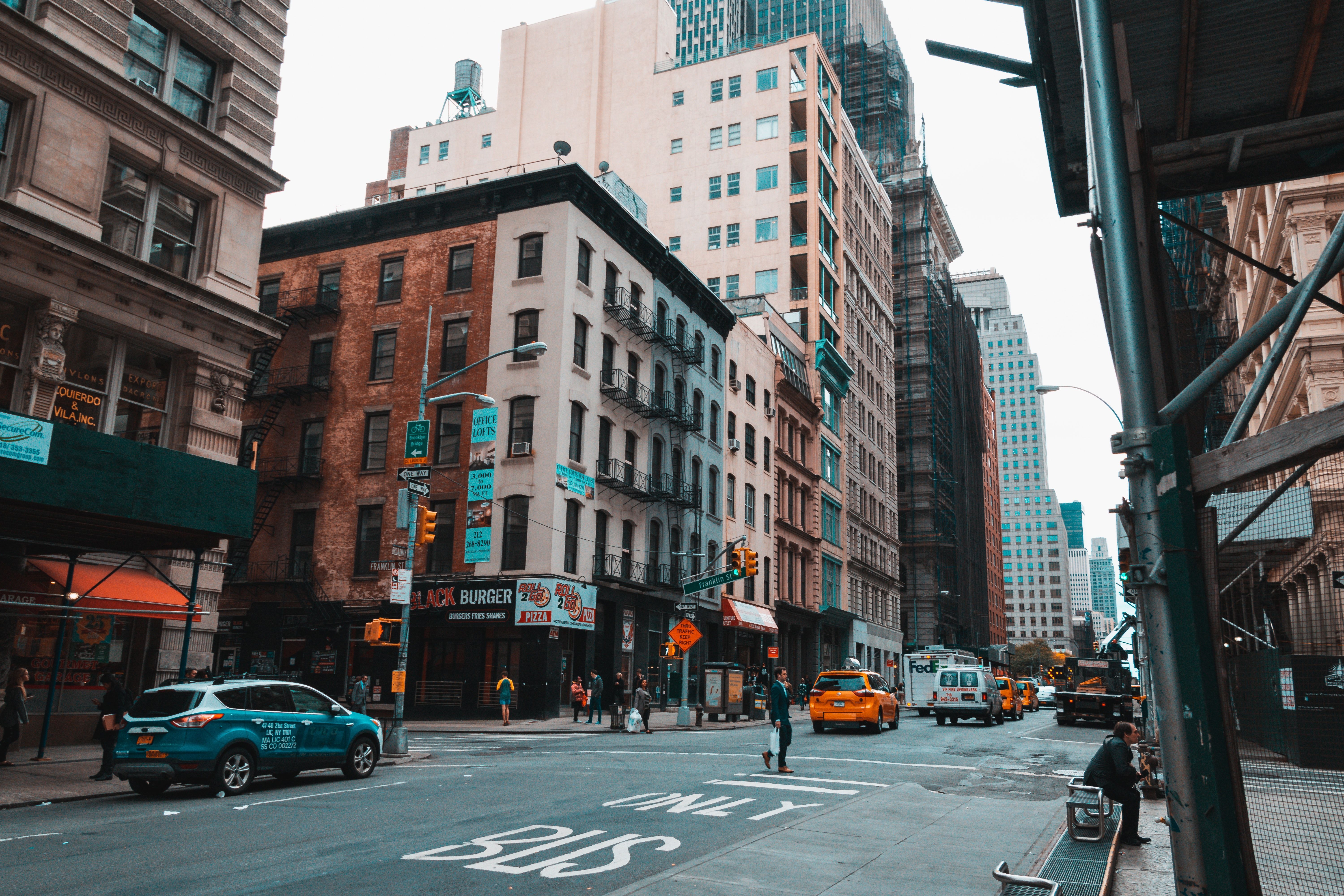 A busy street in New York City with tall buildings and cars. - New York