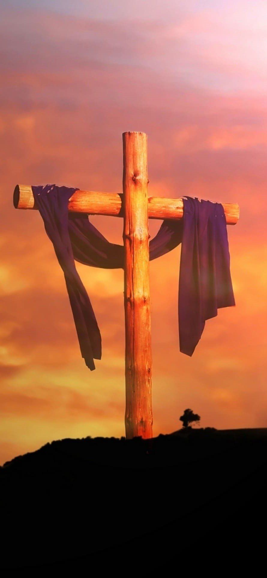 A cross with purple cloth on it on a hillside at sunset. - Cross