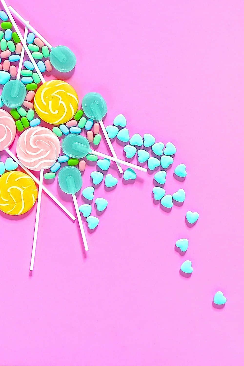 A flat lay of colorful candies on a pink background - Candy