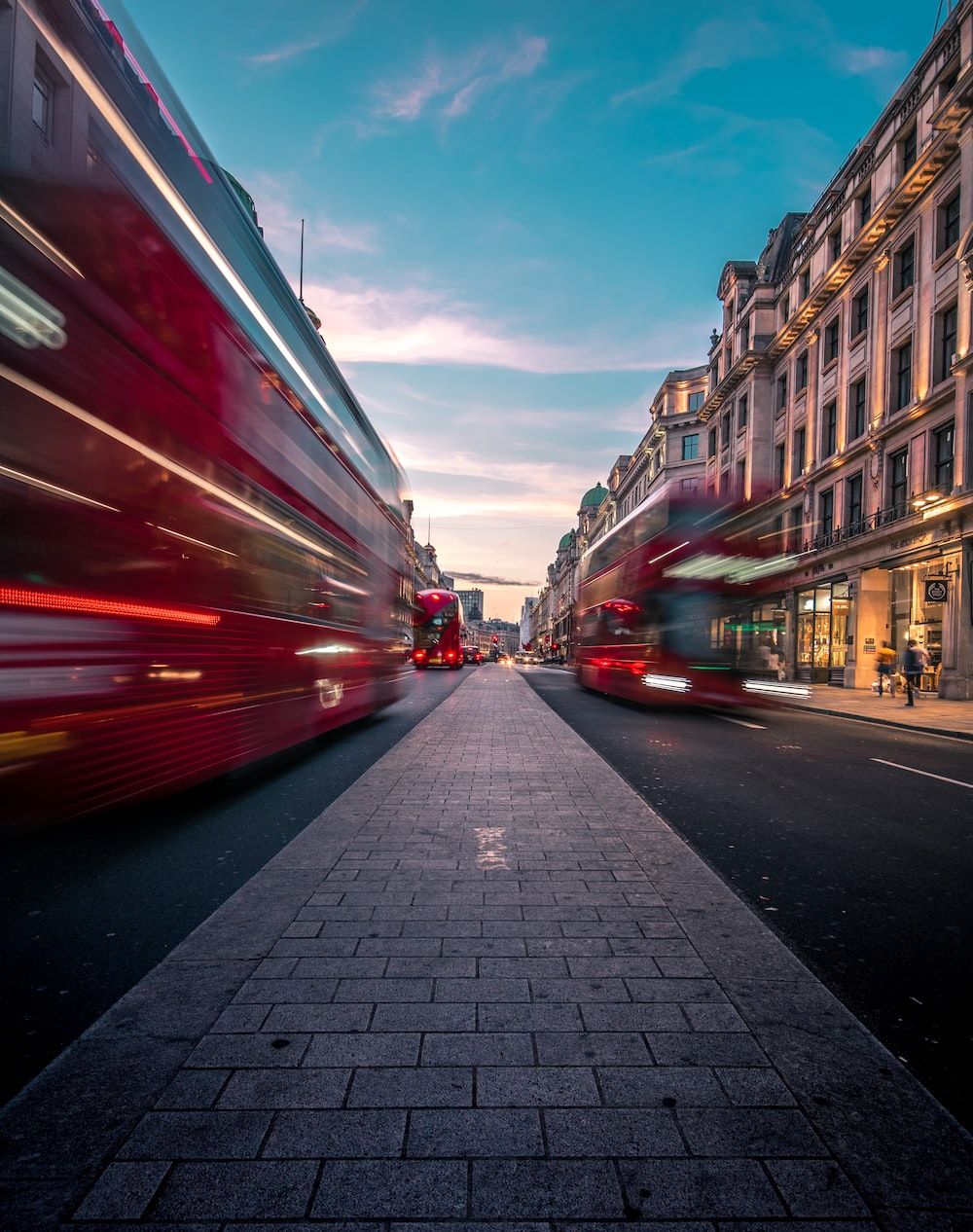 Two red double decker buses on a city street - London