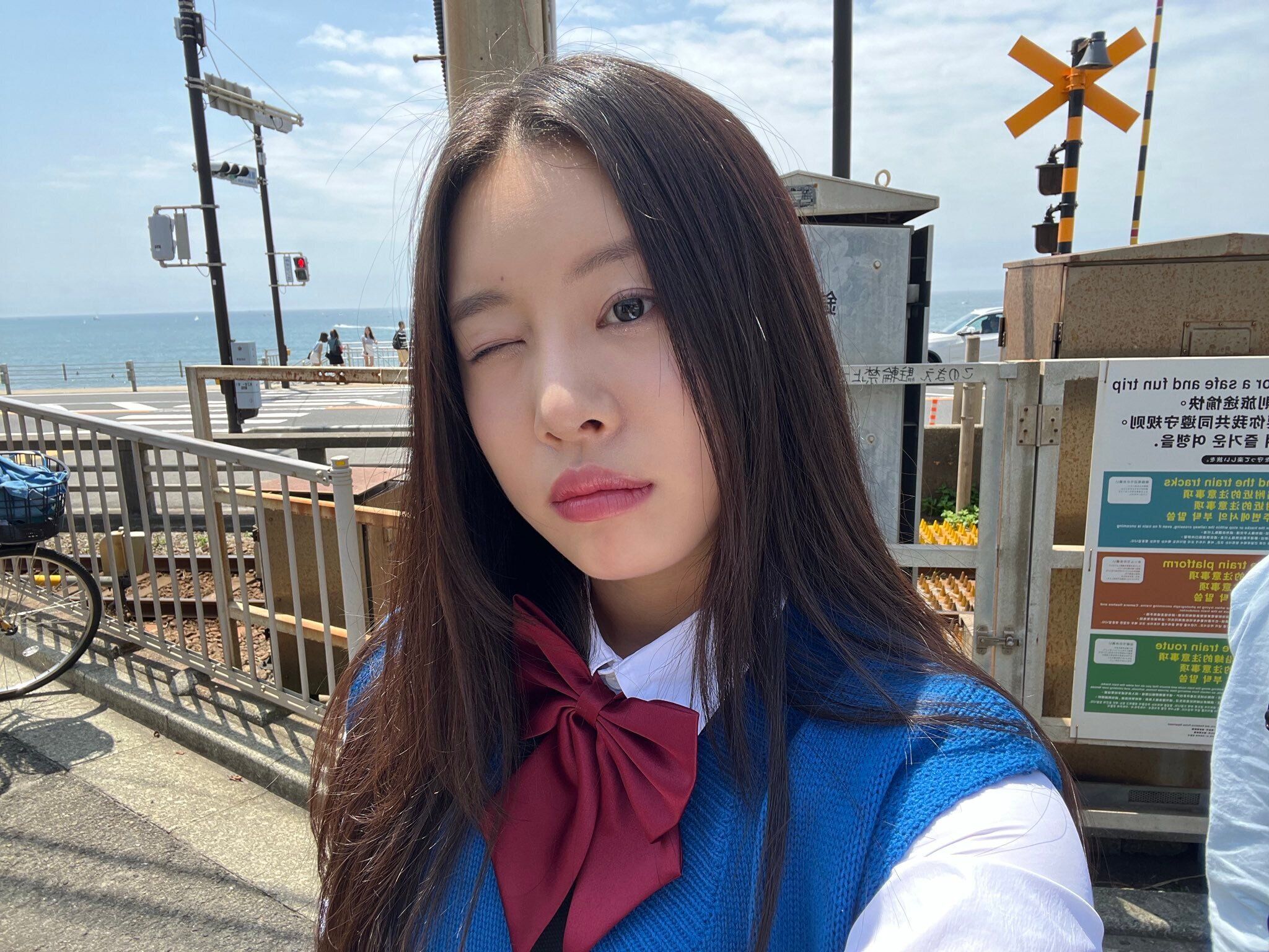 A selfie of a woman with long dark hair, wearing a blue and white school uniform. - FIFTY FIFTY