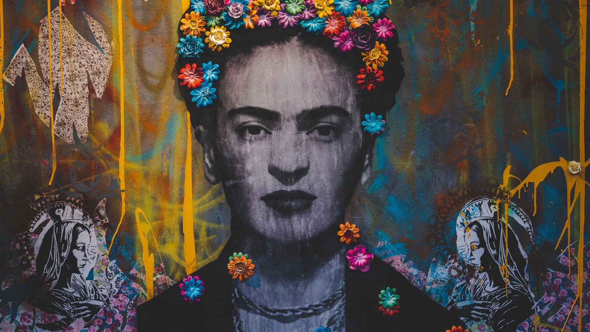 A black and white photograph of Frida Kahlo with a colorful flower crown and a necklace of flowers around her neck. - Frida Kahlo