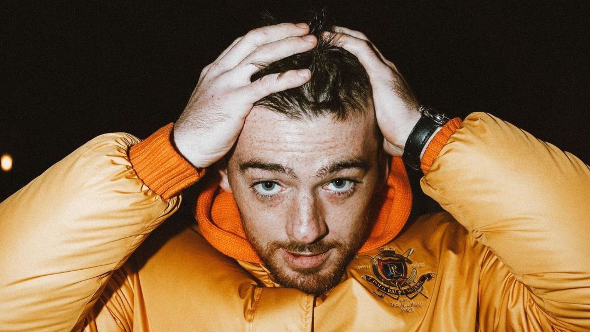 Mac Miller in a yellow jacket holding his head - Angus Cloud