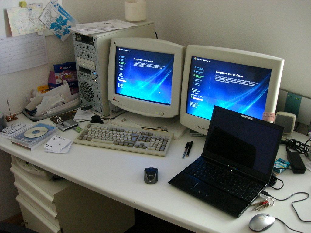 A desk with a laptop, two monitors, a keyboard, and a mouse. - Computercore
