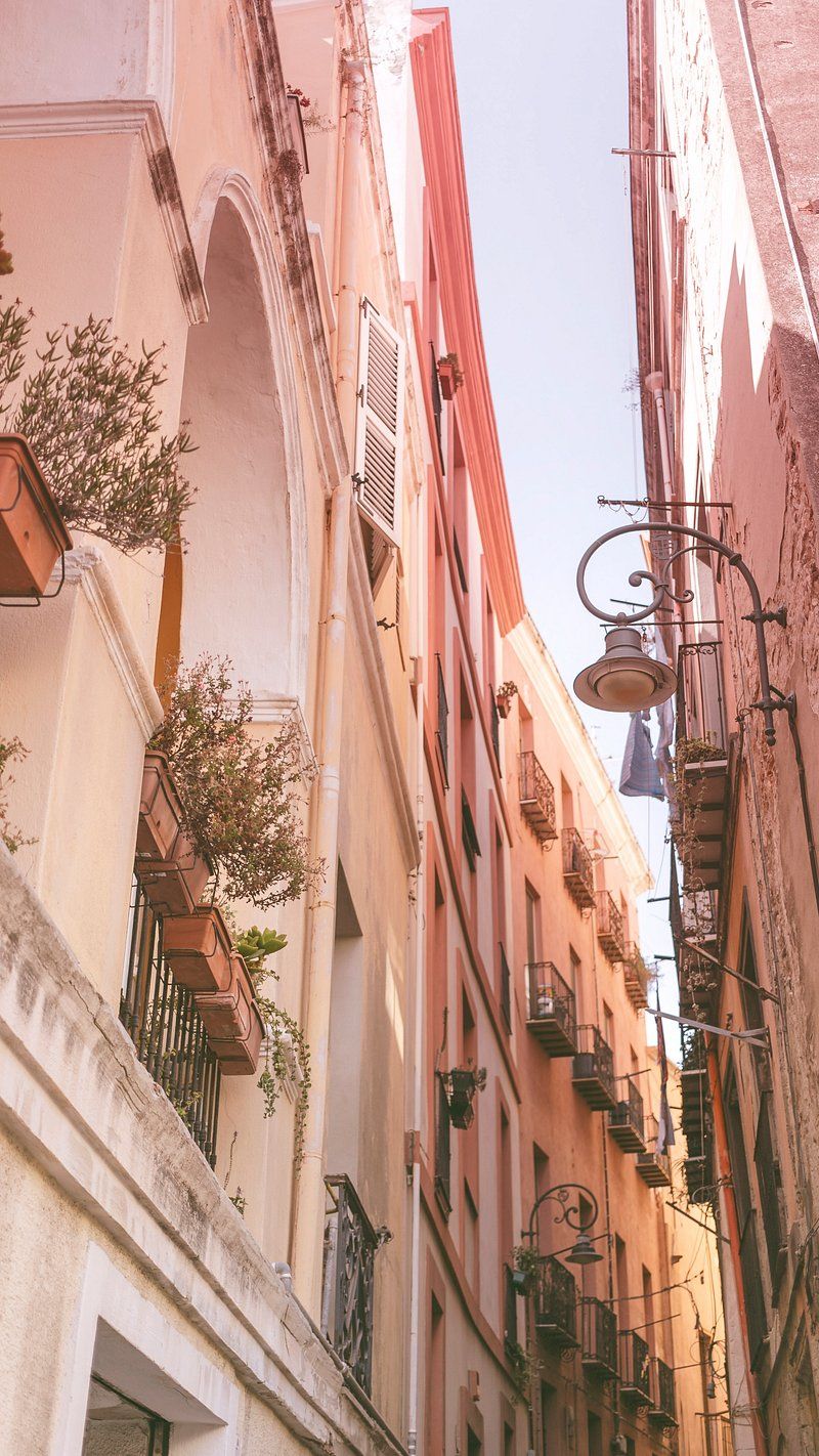 A narrow street with a row of buildings on each side. - Italy