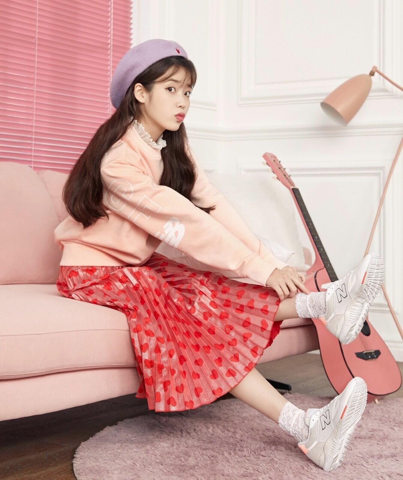 A young girl sitting on a pink couch - New Balance