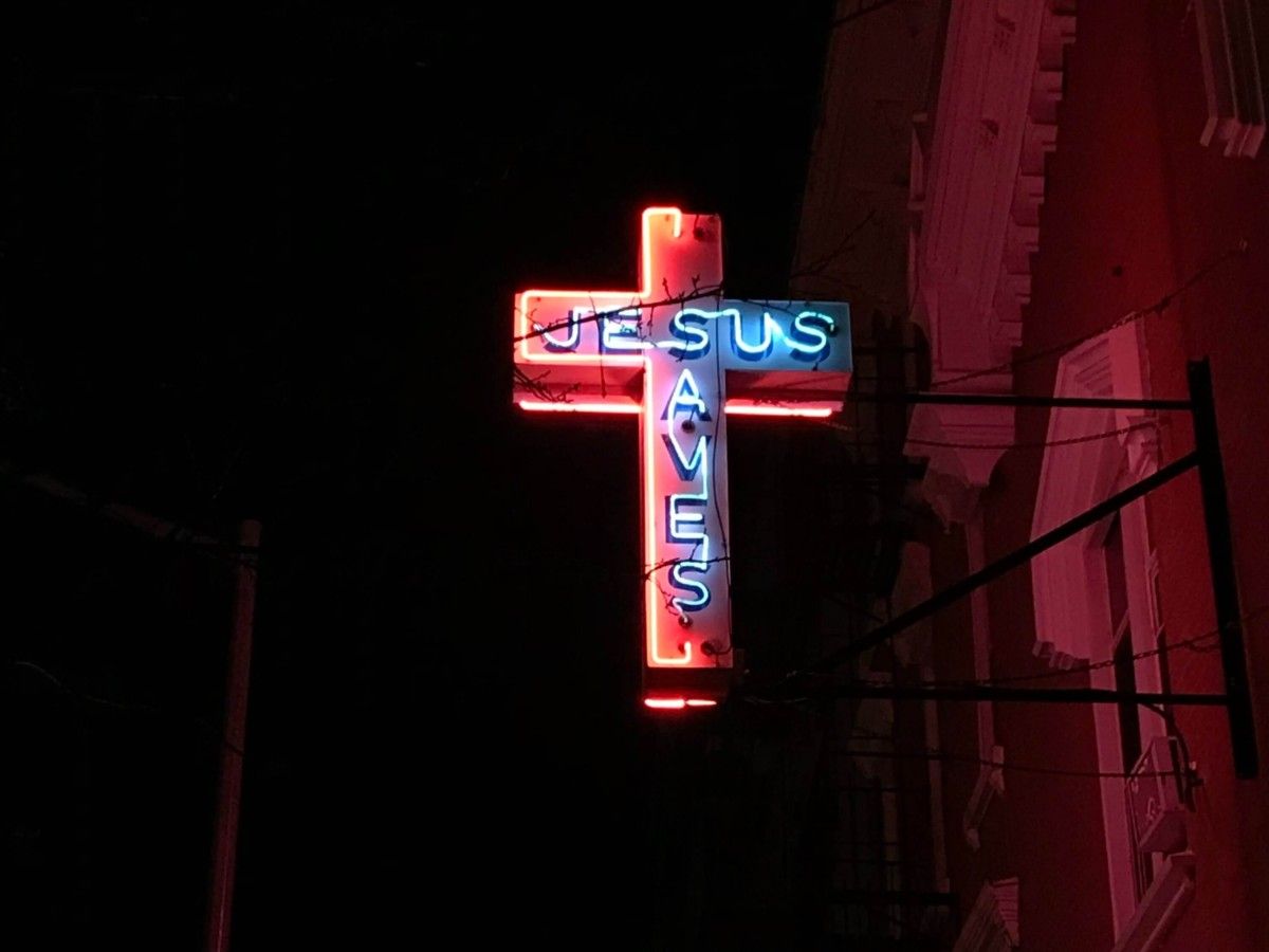 A red neon cross with the word Jesus on it. - Jesus