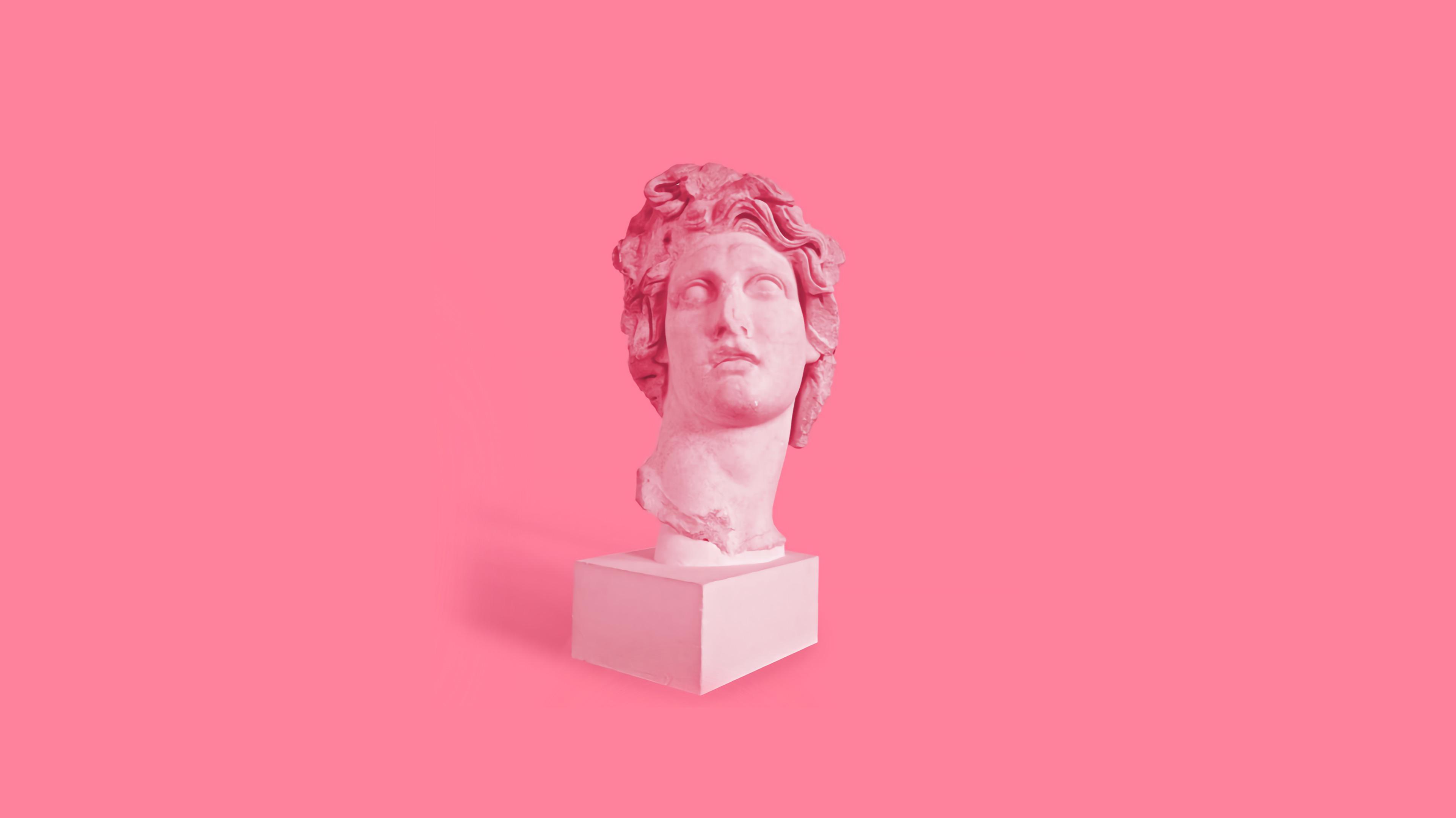 A pink and white sculpture of a man's head on a pink background - Statue