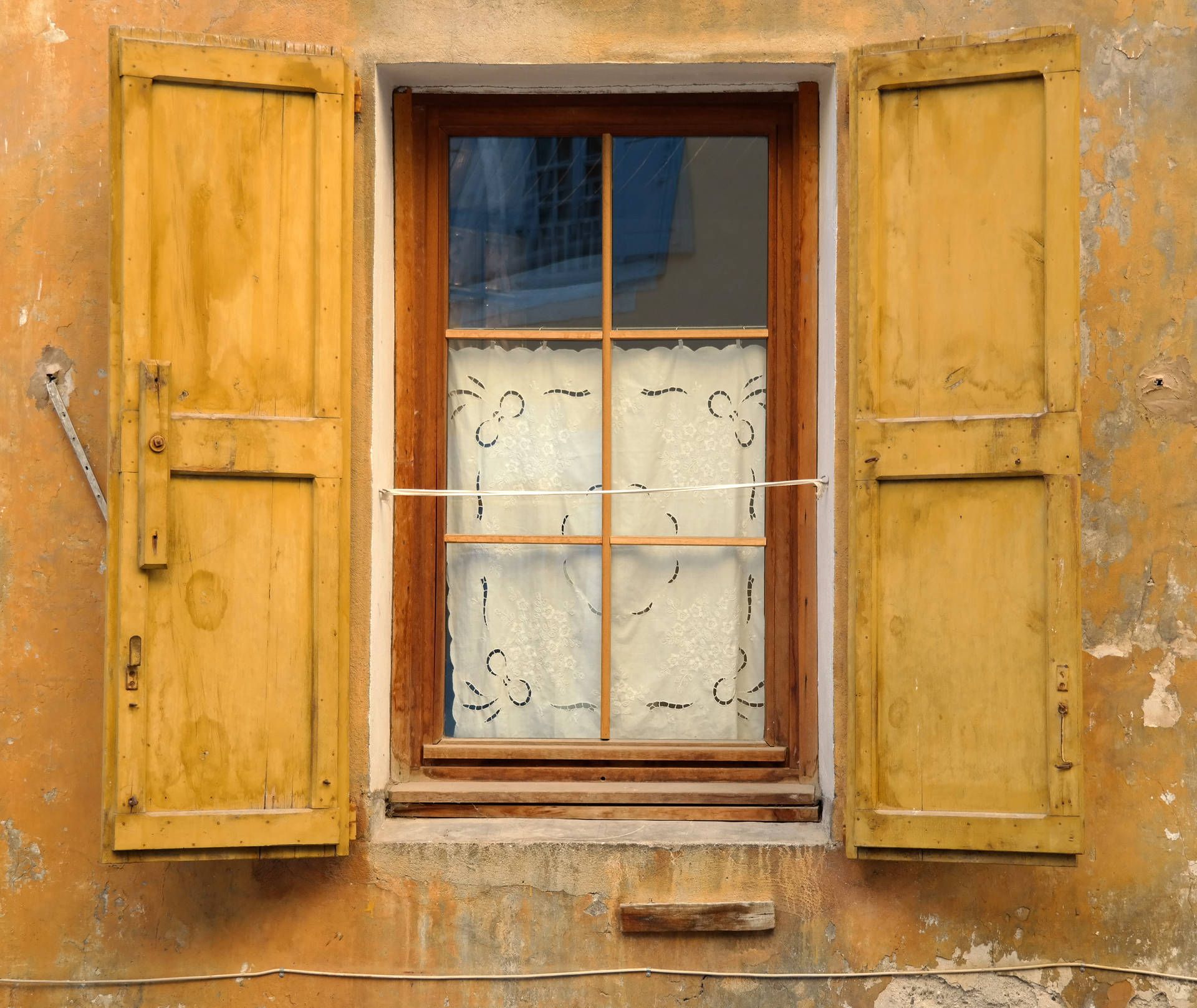 A window with yellow shutters on a yellow building. - Windows 11