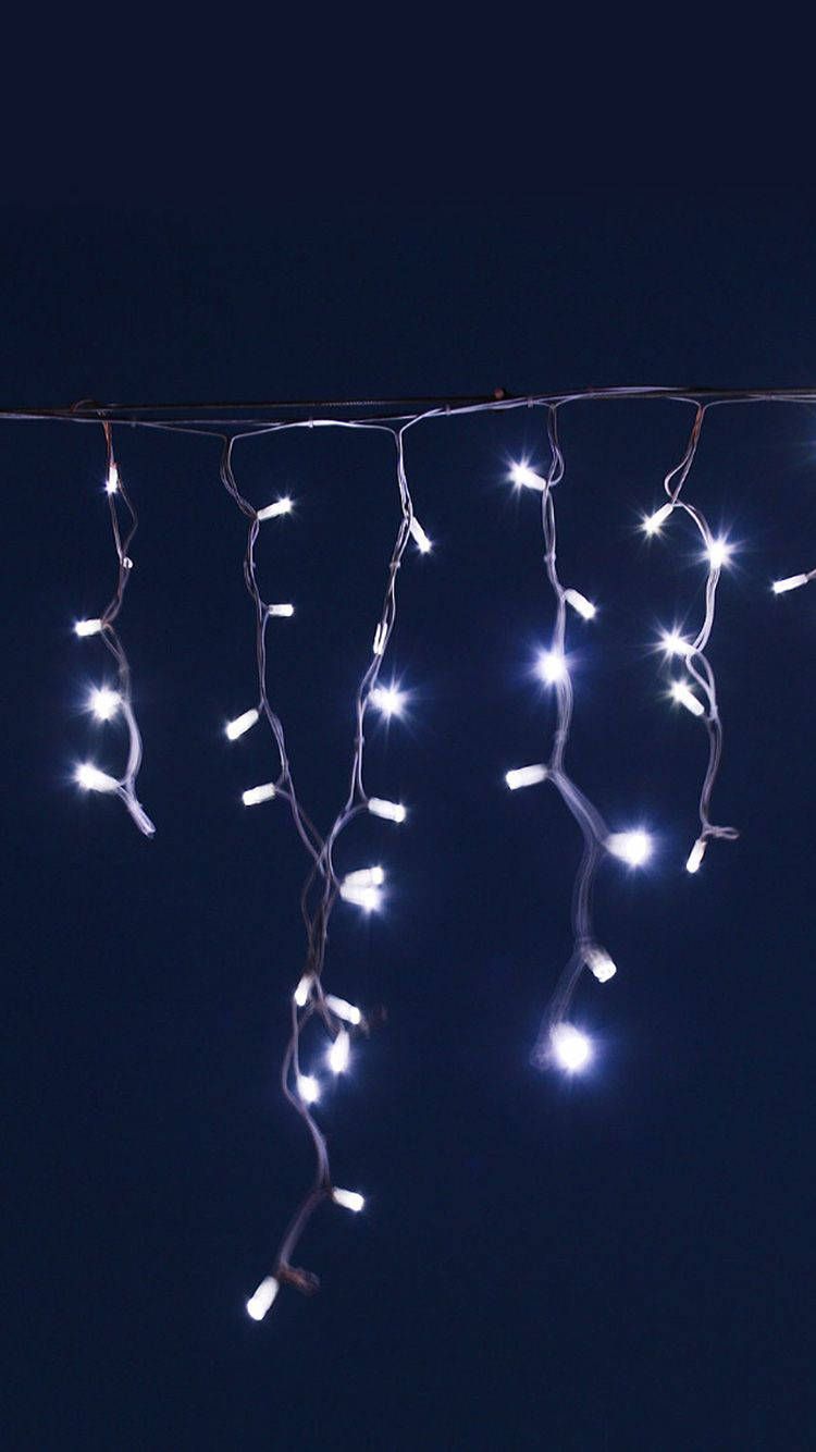 White Christmas lights hanging from a wire against a black background - Fairy lights