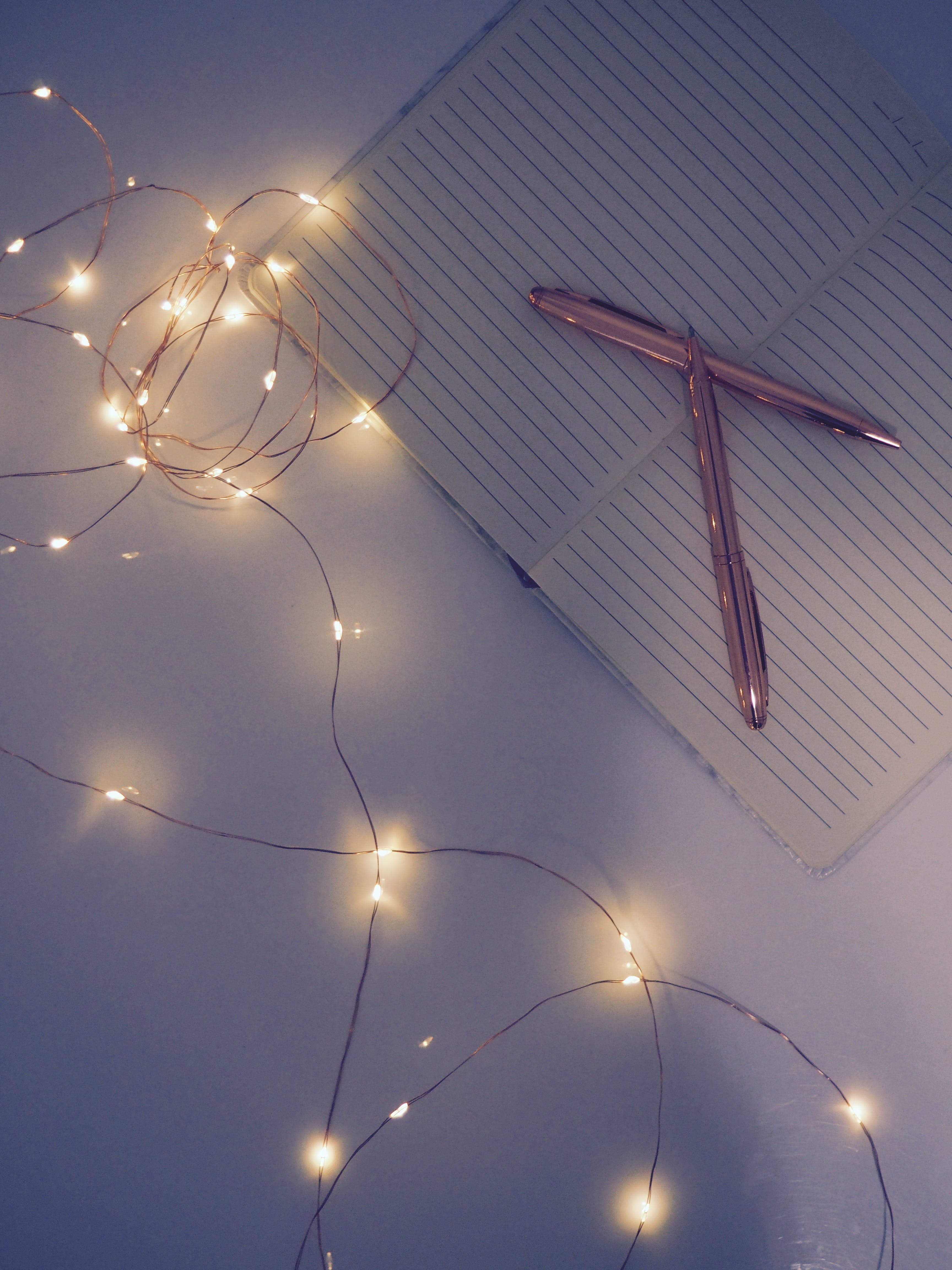 A notepad with a pen and some fairy lights - Fairy lights