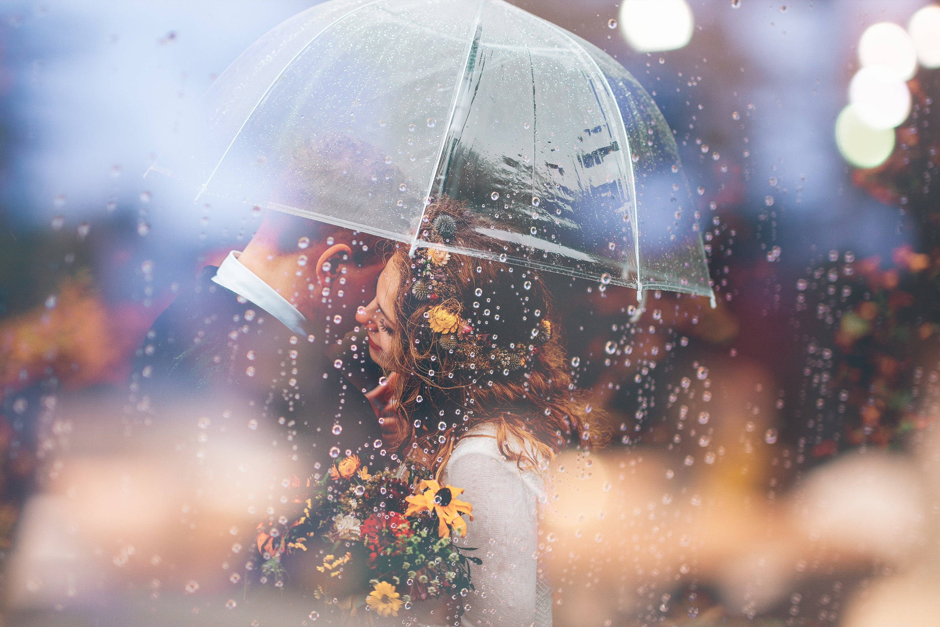 Bride and groom under an umbrella in the rain - Wedding