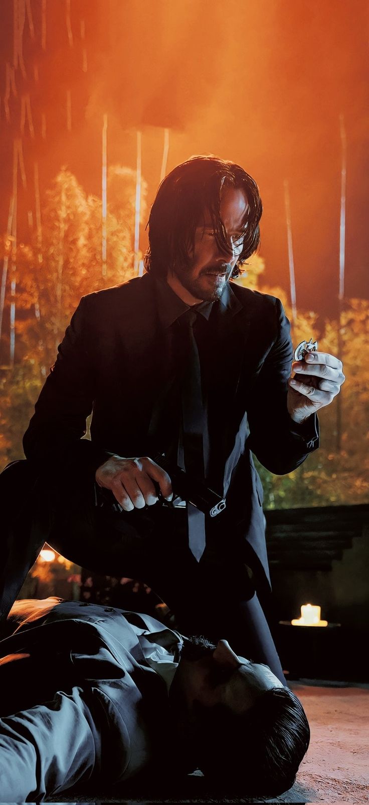 John Wick holding a knife and smoking a cigarette while standing over a dead body. - John Wick