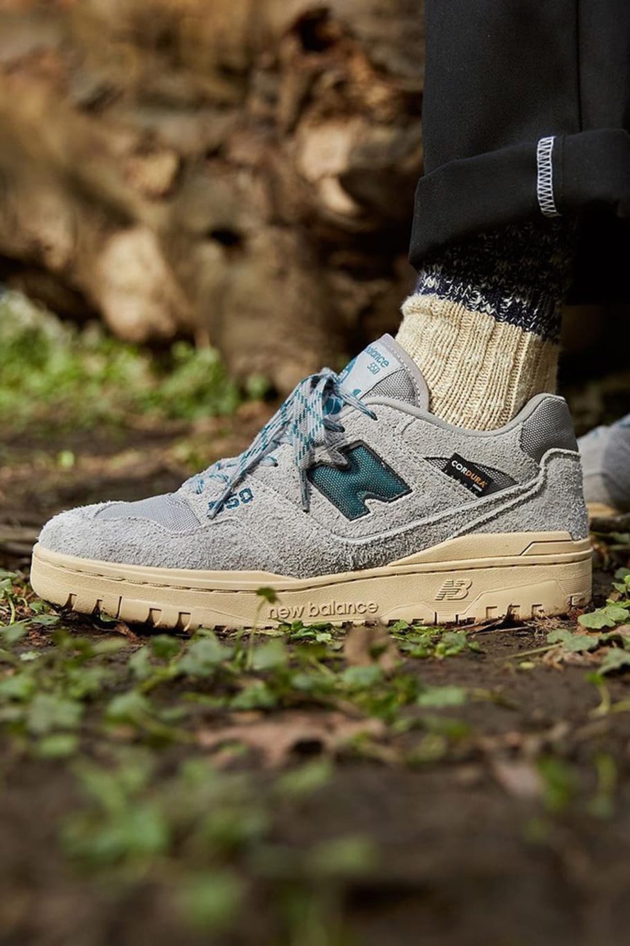 A model wears the New Balance 574 in grey and blue. - New Balance