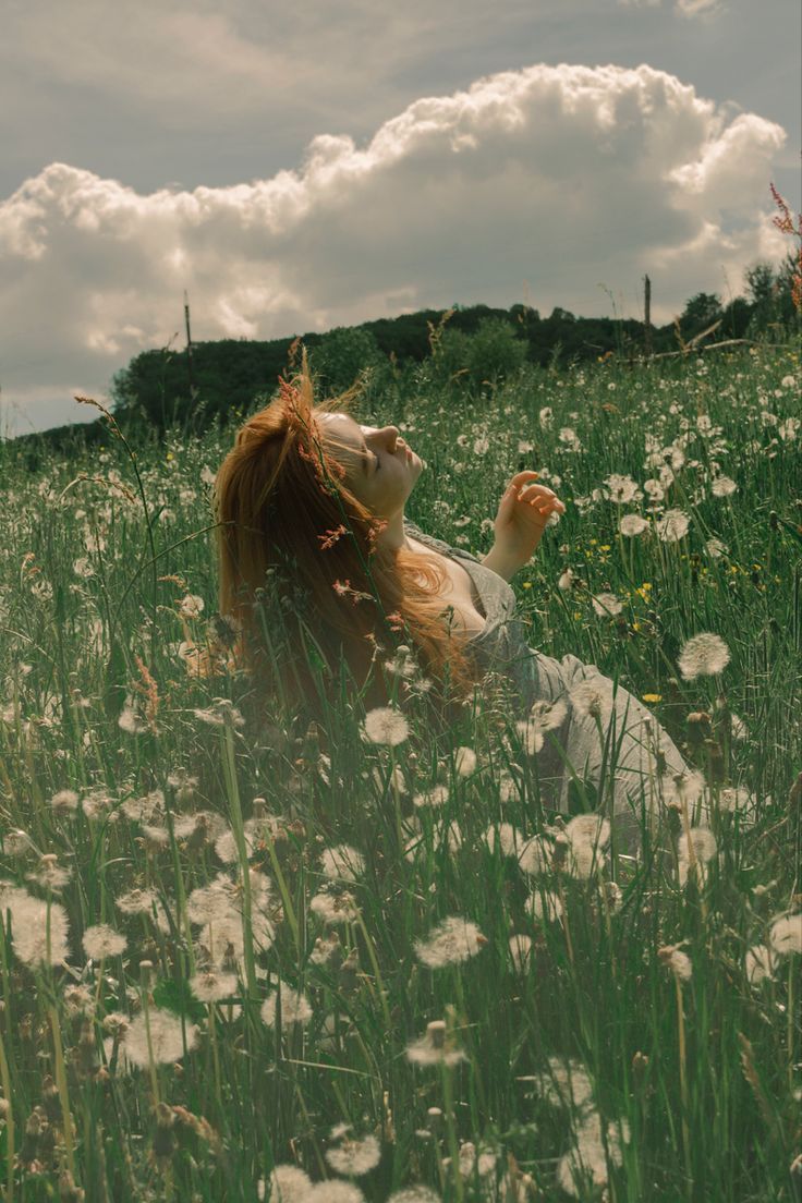 A woman with red hair laying in a field of dandelions - Dandelions