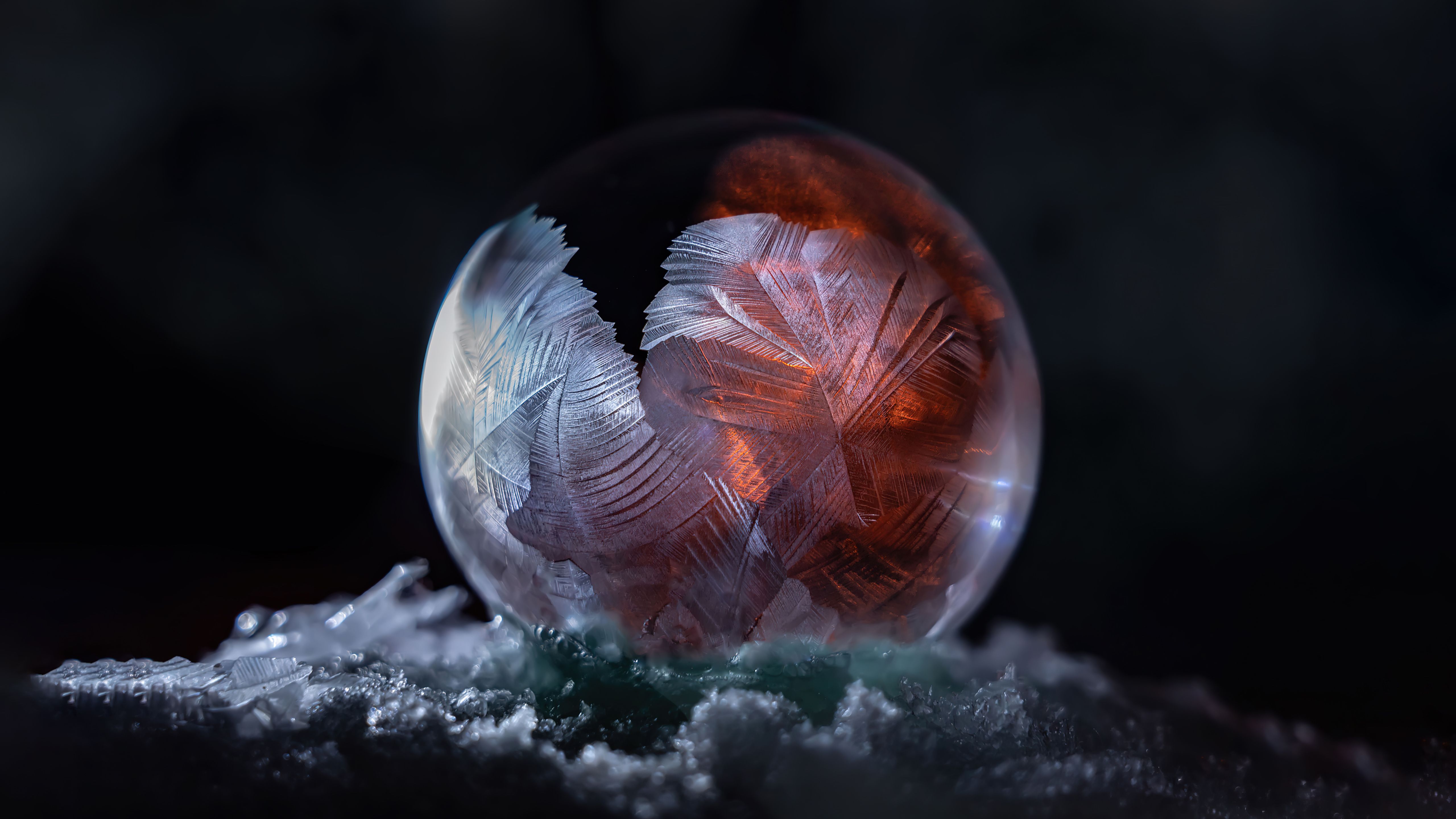 A frozen soap bubble on a bed of snow. - Macro