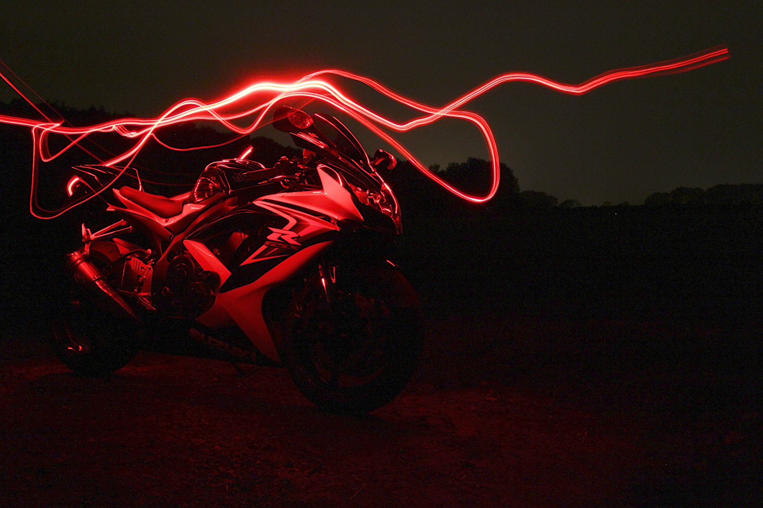 A motorcycle is illuminated by a red light. - Light red, neon red