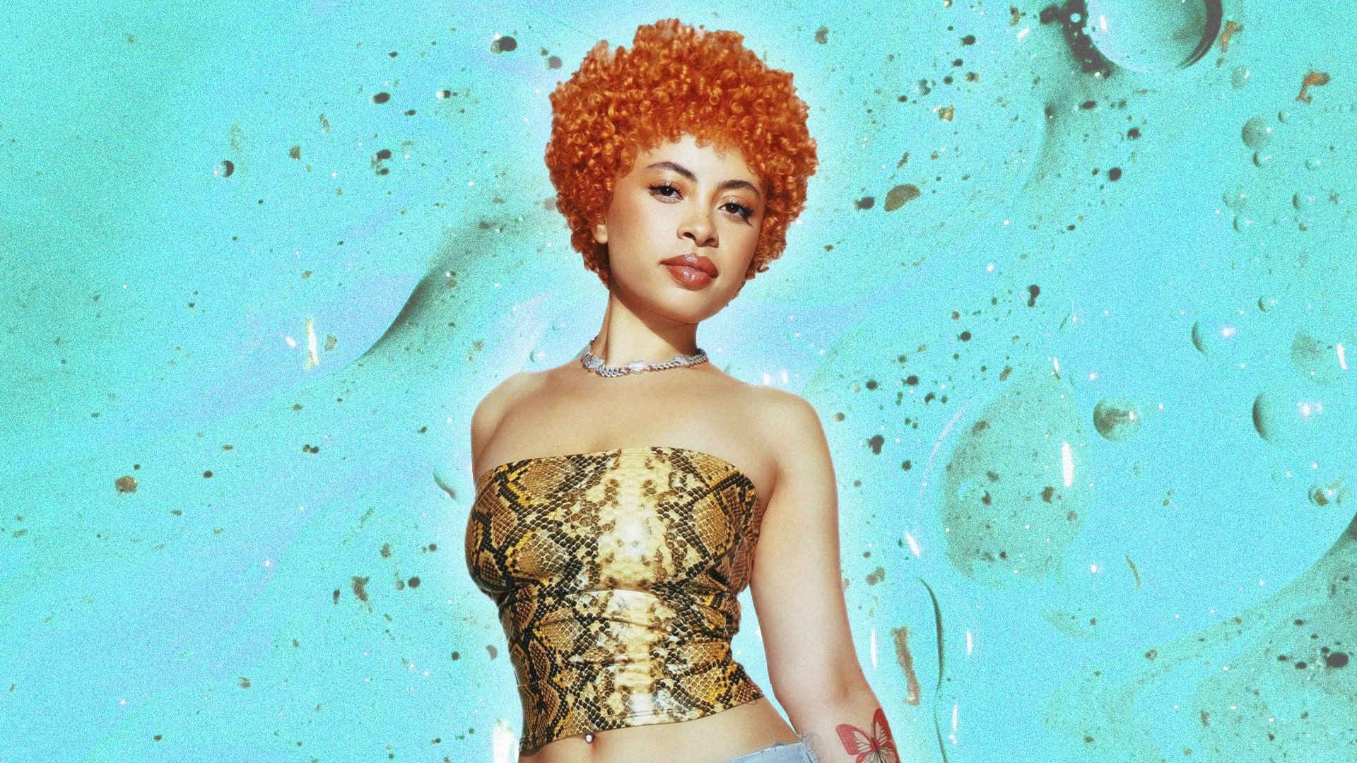 A portrait of a woman with orange hair, wearing a gold snakeskin crop top and pants. - Ice Spice